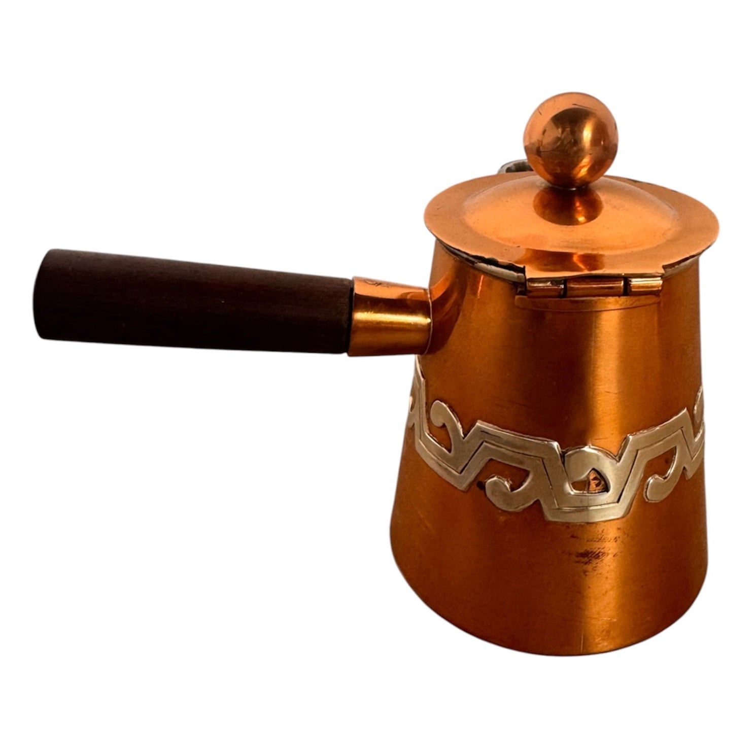 The set includes a large, rectangular, hammered copper tray with geometric openwork handles. Resting on the tray is a tall, slightly tapered copper coffee pot with a wooden handle, a matching smaller creamer pitcher with a similar wooden handle, a lidded sugar bowl, and a tiny matching metal cup or jigger. To the right off the tray sits a large, spherical copper water pitcher or jug with a wide mouth and ice lip.