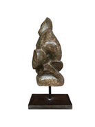Figural sculpture in the Shona style, Zimbabwe. Two abstracted figures are intertwined, carved from greenish-brown soapstone. Sculpture rests on a dark iron stand.