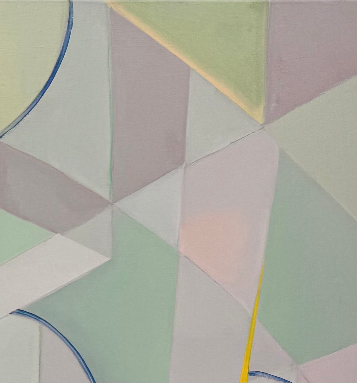 An abstract, horizontally oriented geometric oil painting framed in light natural wood. The composition features a complex, cubist-like lattice of interlocking planes, sharp angles, and transparent shards rendered in a soft, muted palette of pastel greens, lavender-grays, pale blues, and subtle pinks. Intersecting this subdued background are thin, dark blue sweeping arcs that trace circular movements across the canvas. Piercing through the composition are several sharp, dynamic, bright yellow shards shaped