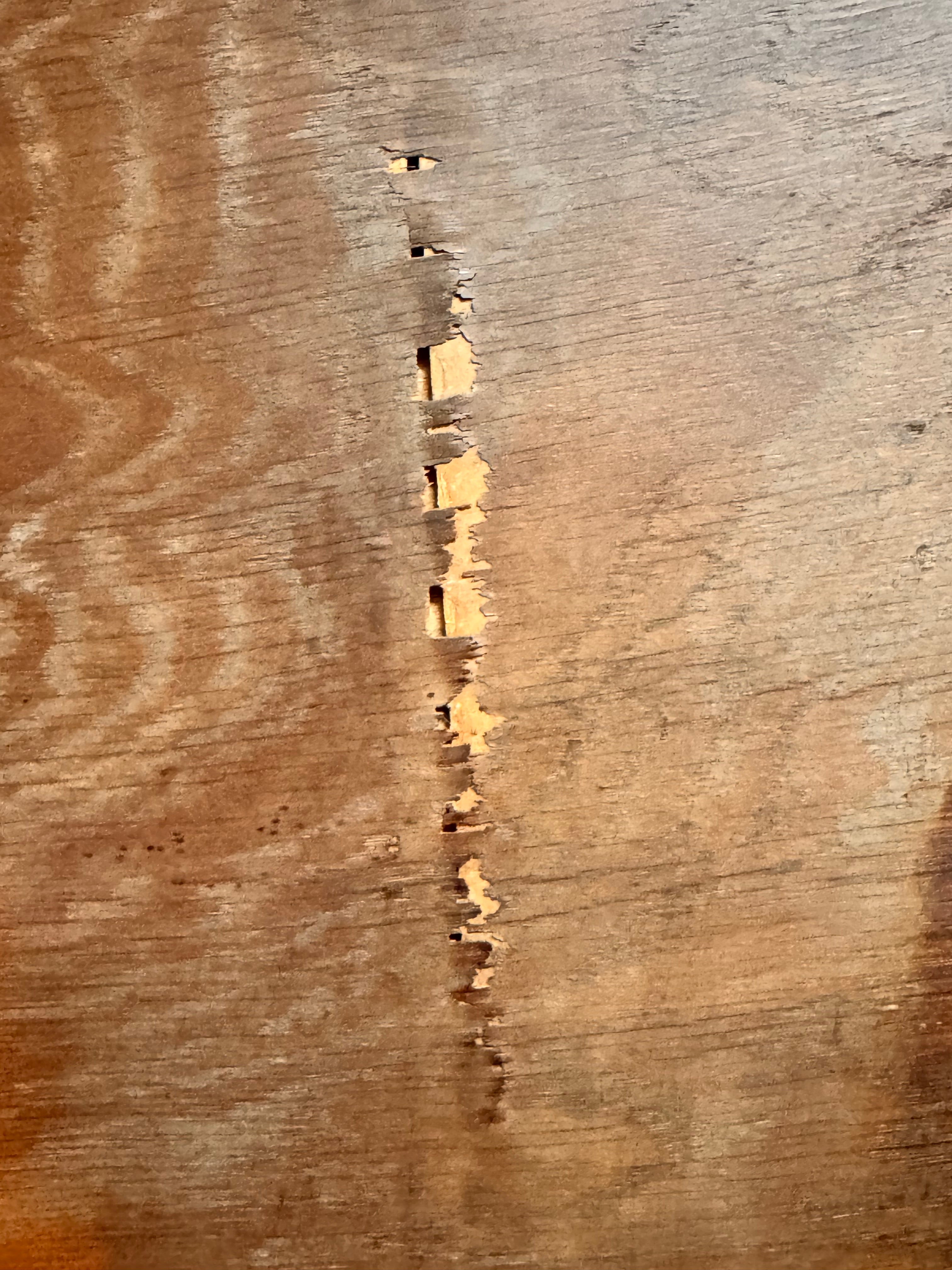 An oval-shaped mirror featuring a wooden frame and an ornate metal crest at the top.