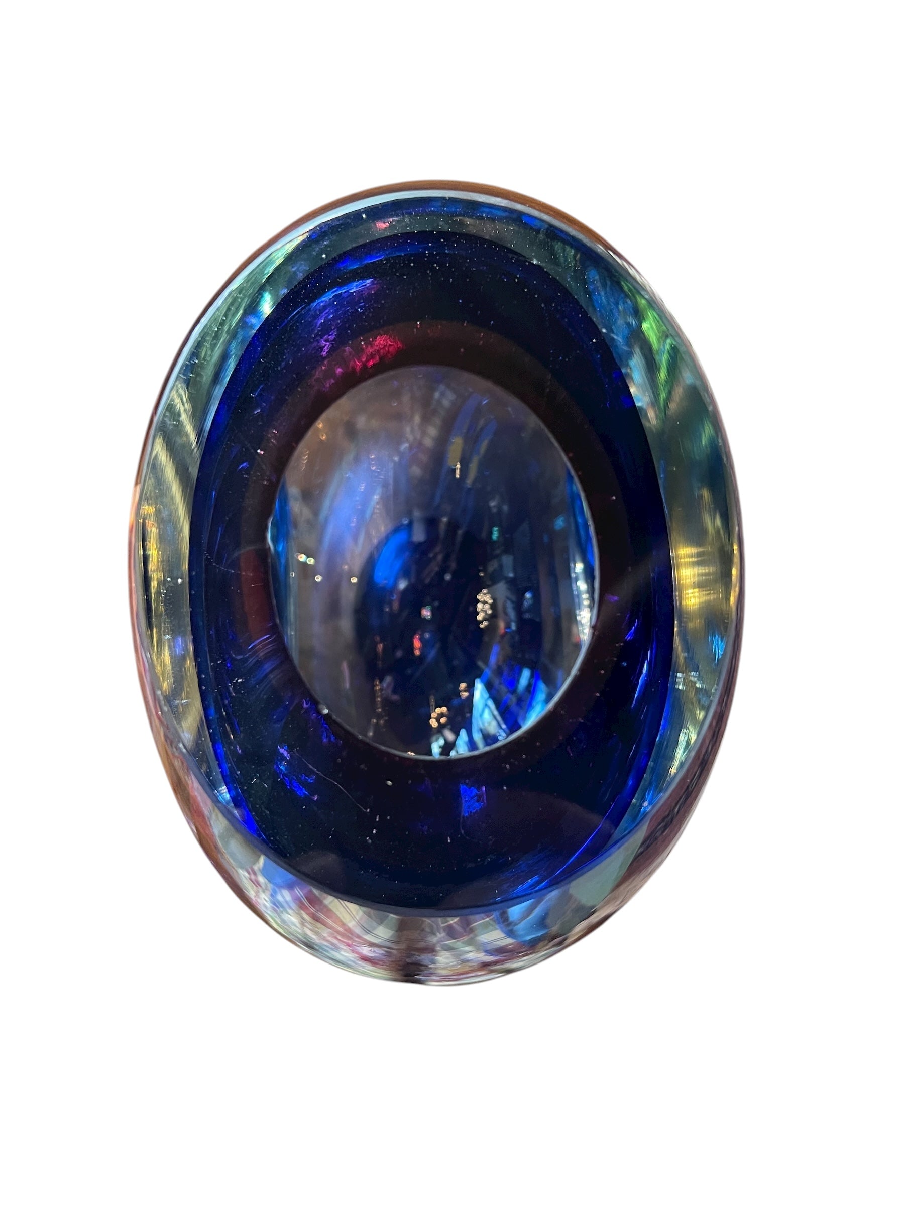 Sommerso glass vase with flattened sides creating a fish-eye effect, featuring cobalt and indigo colors and internal bubbles.