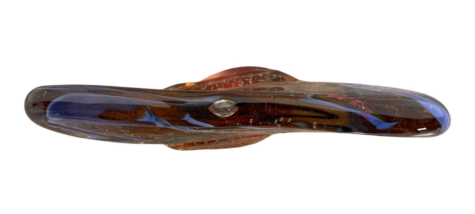 An asymmetrical Murano art glass sculpture with a heavy, biomorphic form. The piece is composed of thick, translucent smoky-amber glass with abstract, fluid bands of deep blue and dark brown swirling throughout the upper rim and sides. A dense pattern of tiny, controlled air bubbles is suspended inside the glass, concentrating heavily near the thick, solid amber base.