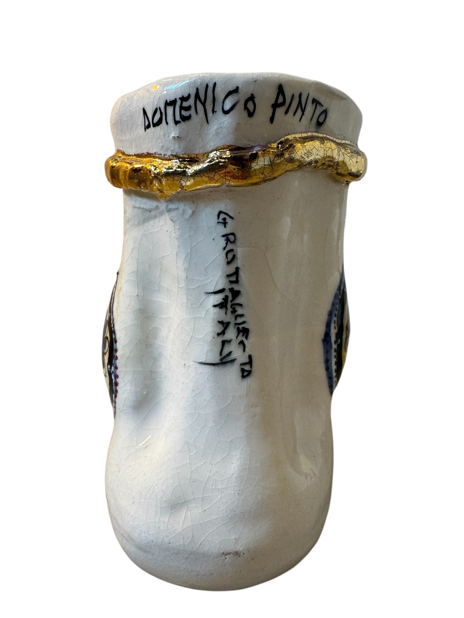 Close-up of a ceramic foot sculpture by Domenico Pinto. The foot is decorated with intricate hand-painted designs inspired by Apulian folklore and accented with 24KT gold. A stylized gilt mask sits atop the foot.