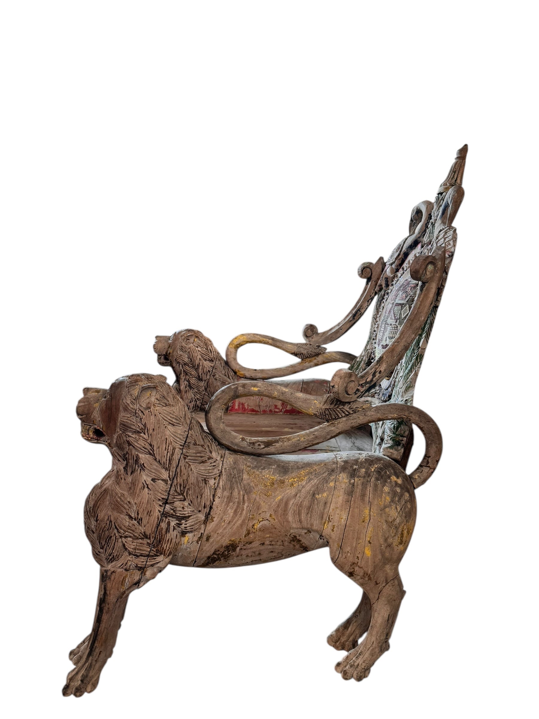 A pair of antique, heavily carved Anglo-Indian style throne chairs featuring lion figures as legs and arm supports, and peacock motifs on the backrests. The chairs have a distressed, multi-colored painted finish.