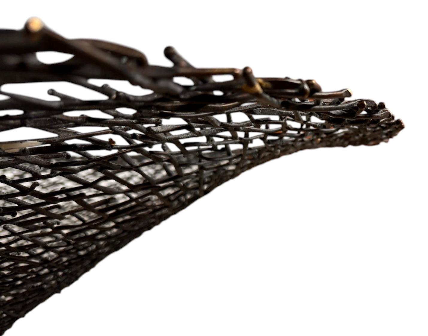 A round metal wall sculpture by Michael Aram, viewed from the front against a stark white background. The piece is composed of a dense, intricate lattice of fine, dark metal wire or twigs woven together to create a textured, web-like pattern. The structure curves inward like a funnel or a vortex, sloping down toward a clean, circular opening in the exact center, creating a strong sense of depth and dimensionality.