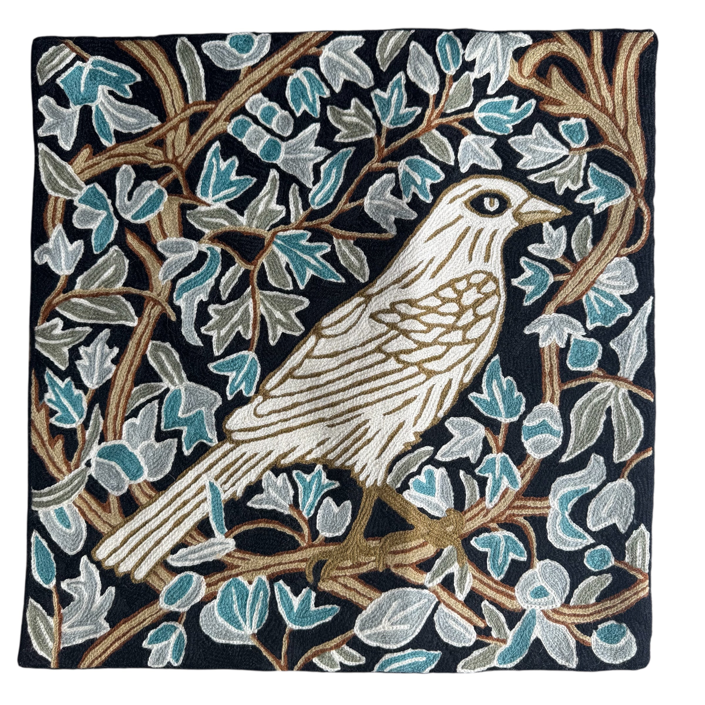 Decorative pillow with bird and leaf pattern on a black background. Vibrant cross-stitched pillows from India with various artistic designs, sourced in Aix-en-Provence.