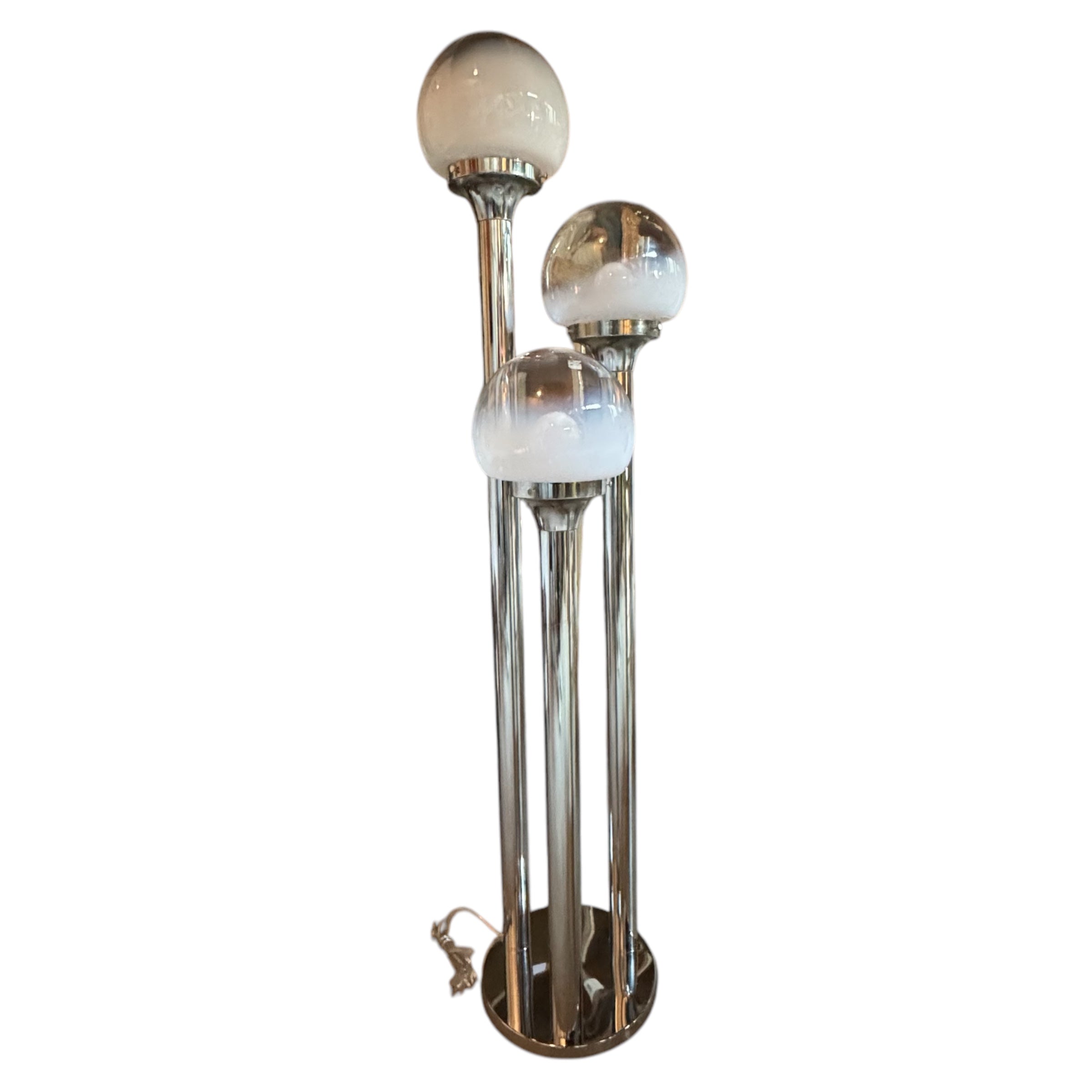 A polished chrome steel floor lamp with three cascading hand-blown Murano glass shades, with a patinated finish and a Mazzega brand mark on the base.