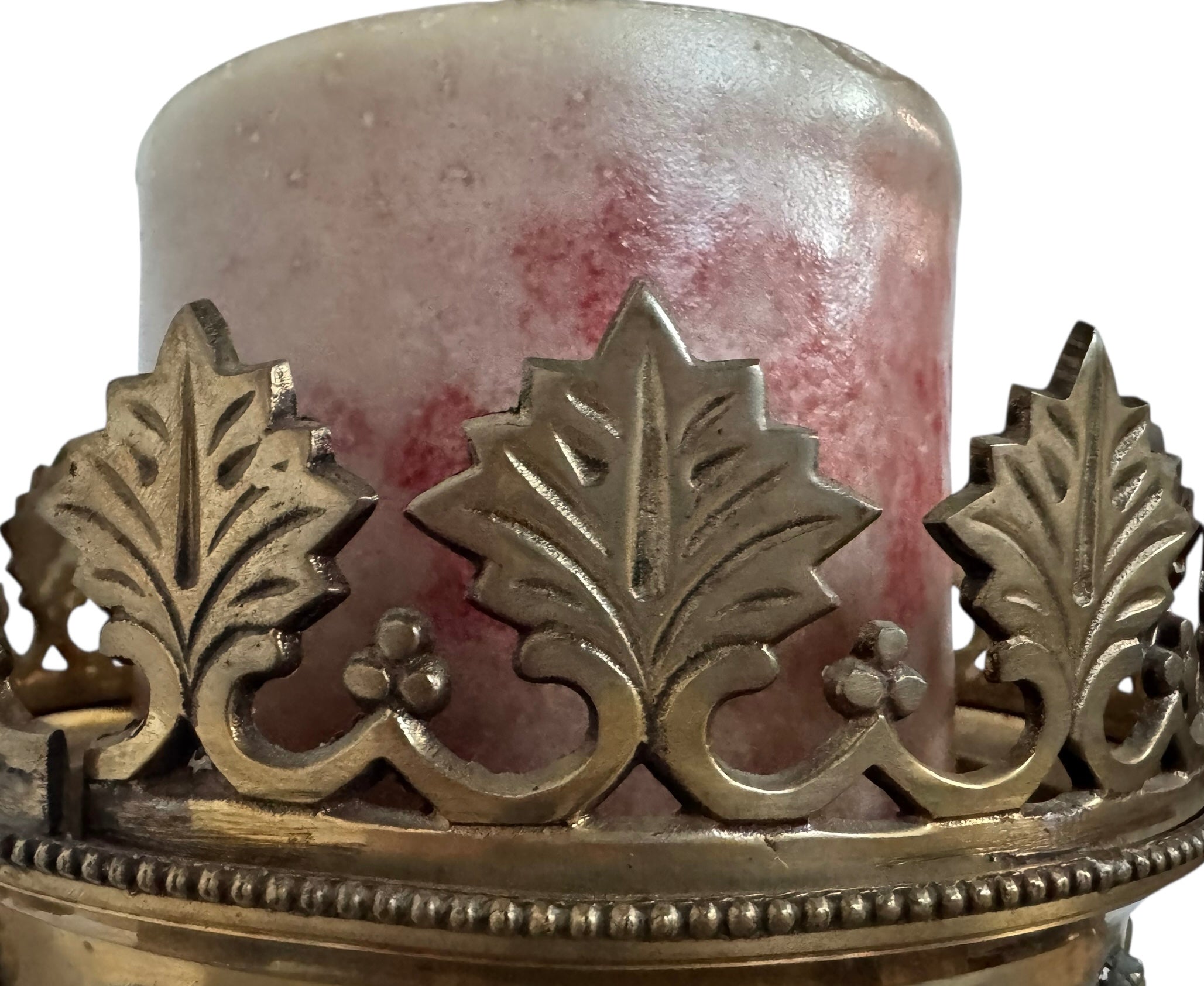 A tall, ornate, antique brass or bronze Gothic church candlestick holder with a pink candle in the top.