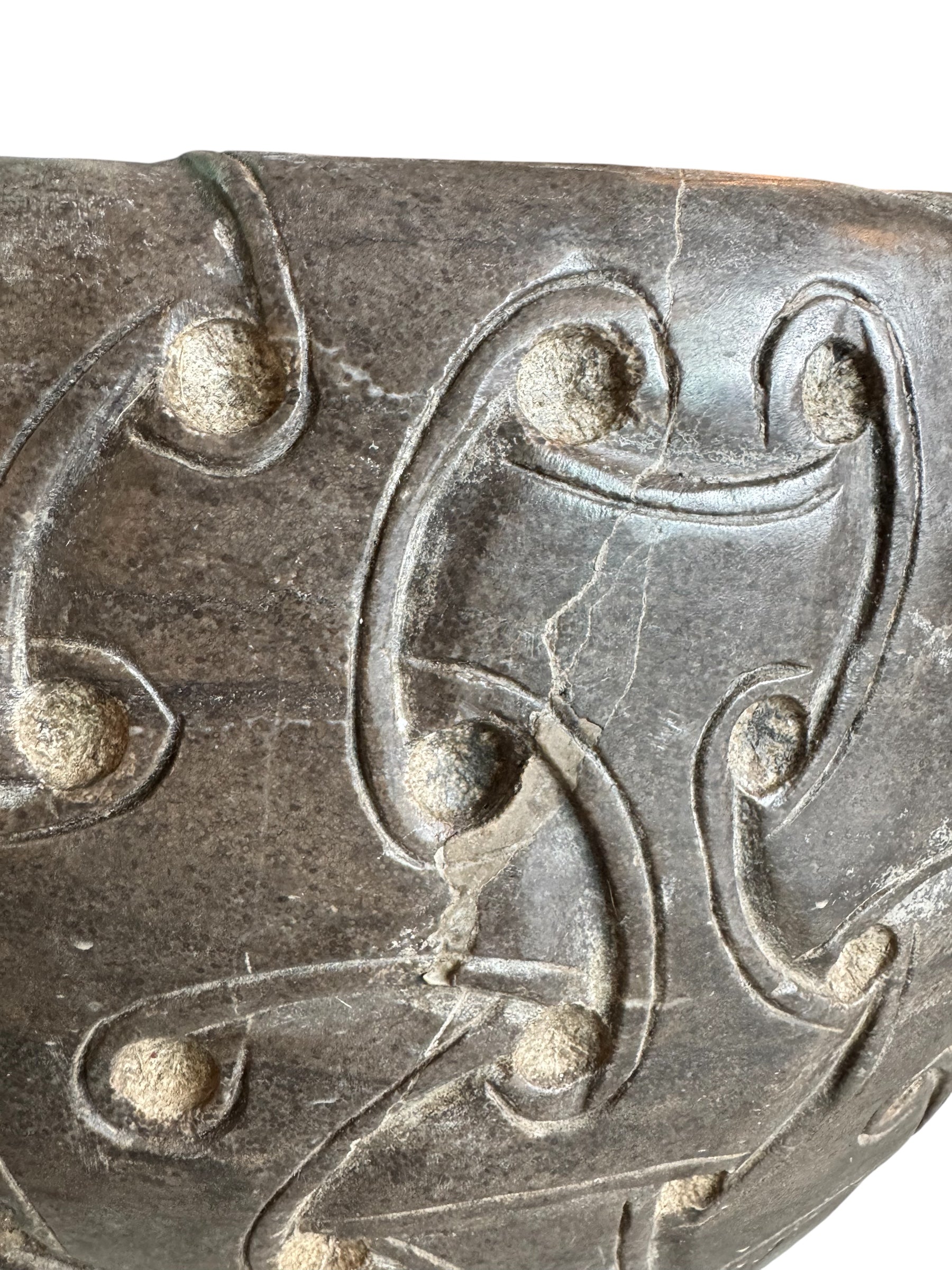 A heavy stone planter, featuring an intricate, hand-carved pattern resembling Celtic knot work.
