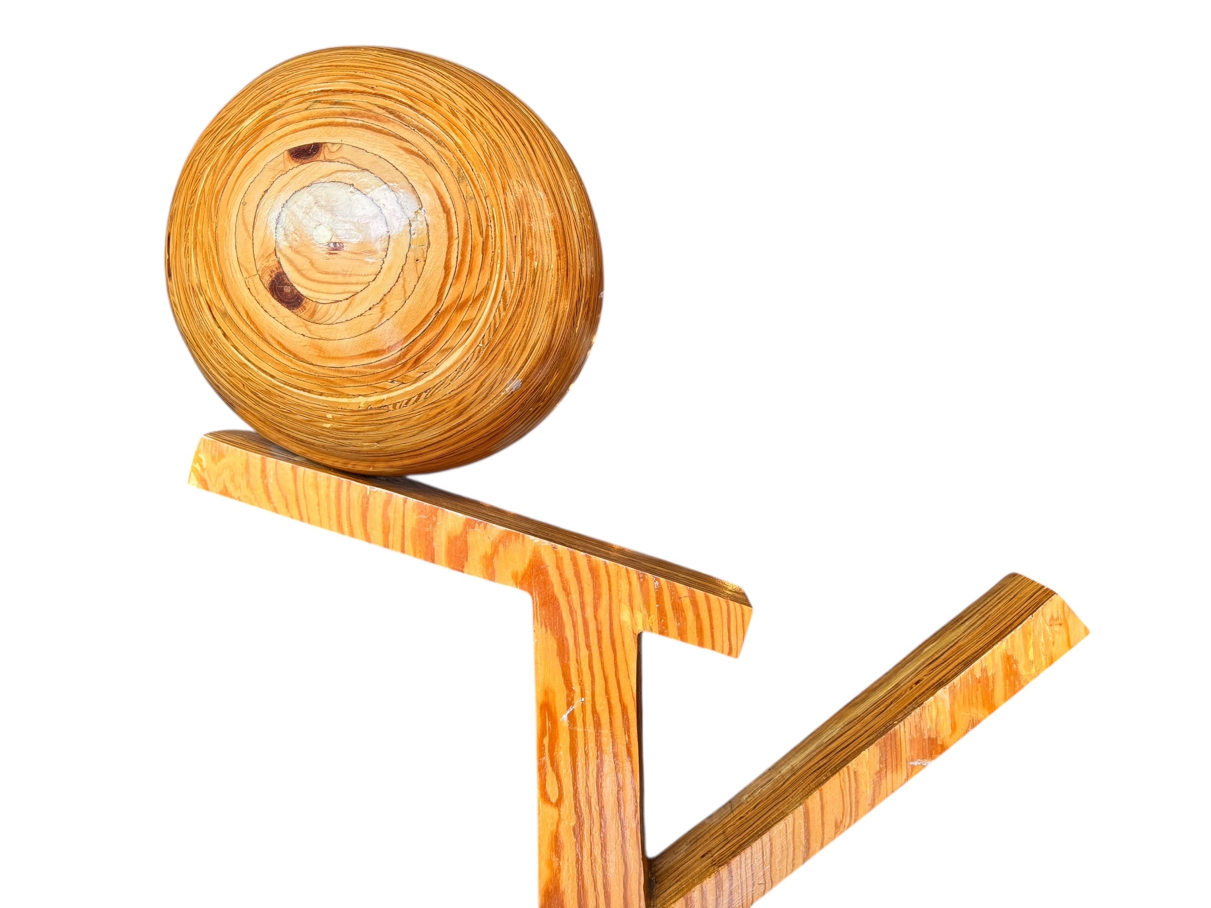 A wooden sculpture featuring a dark square base, a vertical trunk that branches into two angled supports, and a turned wooden sphere resting on the higher support.