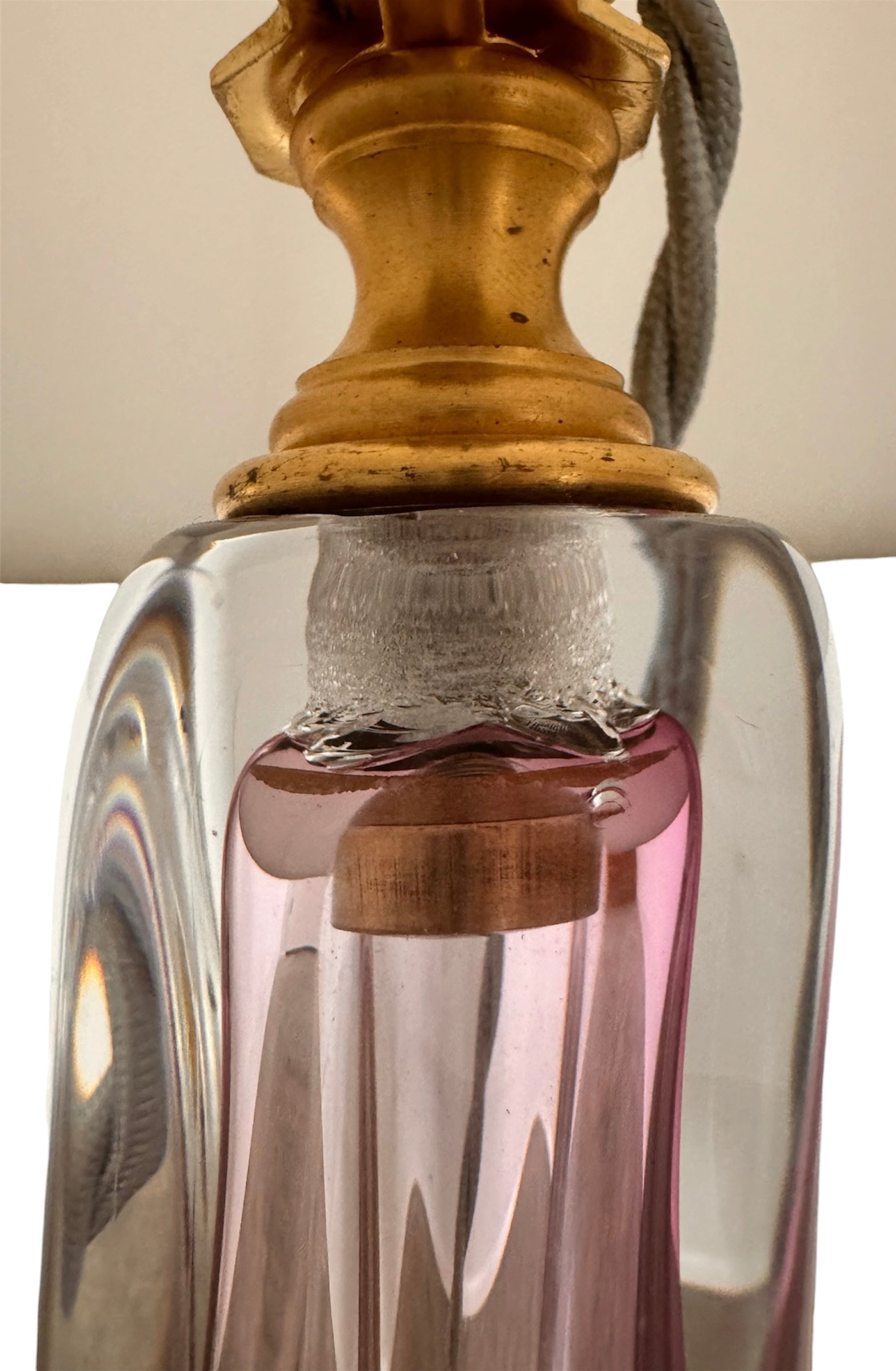 A tall, Mid-Century Modern sculptural table lamp featuring a hand-blown art glass base. The base is crafted in the Sommerso style, with a deep amethyst purple core encased in a thick, clear crystal outer layer that twists upward in an organic, fluid motion. The lamp is topped with a white, knife-pleated empire shade and a clear glass ball finial. The overall design is elegant and slender, emphasizing the contrast between the saturated purple glass and the transparent, light-refracting crystal.