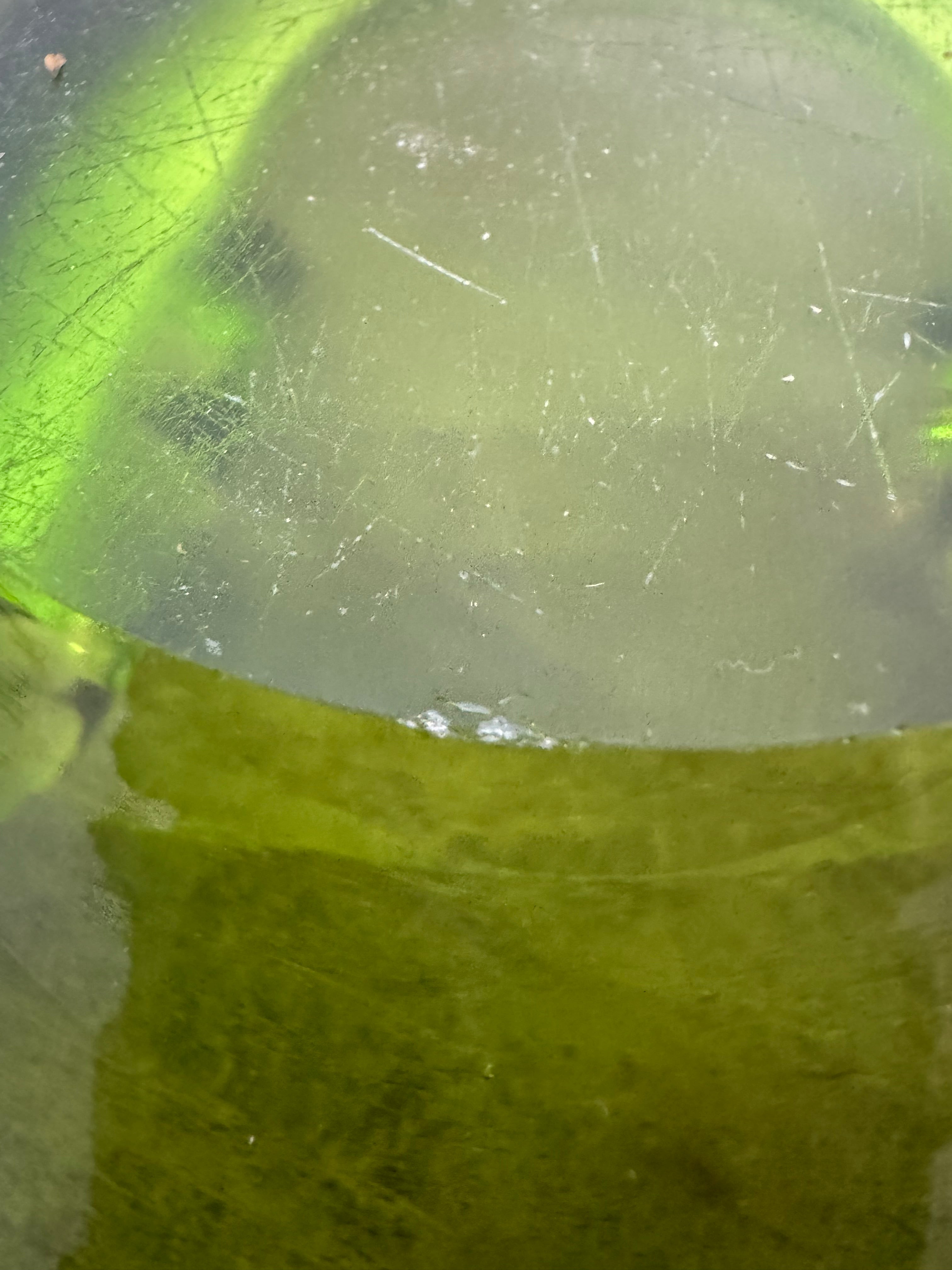 A vintage, Mid-Century Modern, peridot green art glass ashtray or catchall bowl with a curved, free-form design.