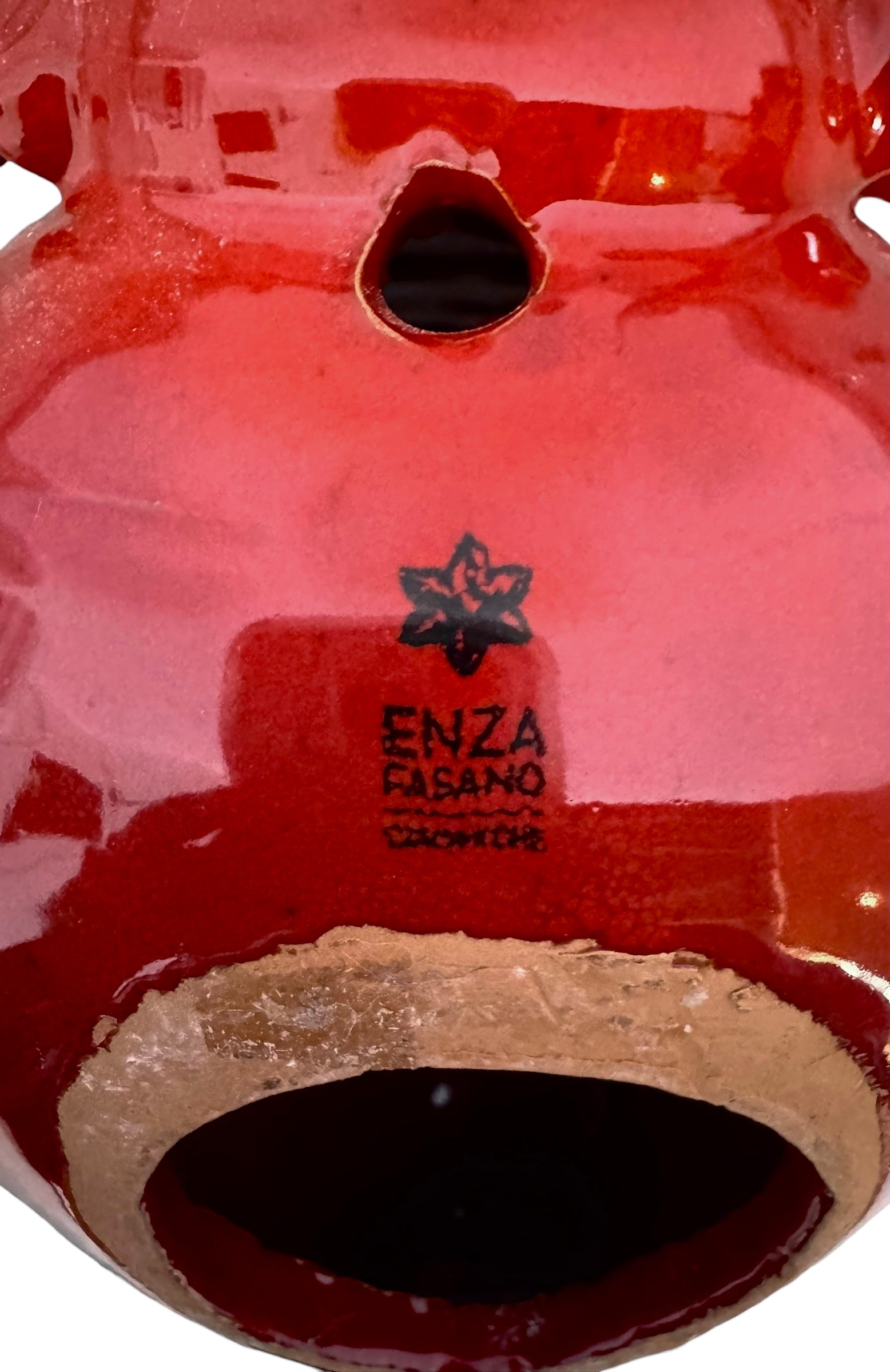 A vibrant, glossy red ceramic sculpture of a rhinoceros beetle by Enza Fasano. The piece features a highly reflective, deep crimson glaze that accentuates its smooth, rounded abdomen and the intricate, jagged textures of its head and horns.