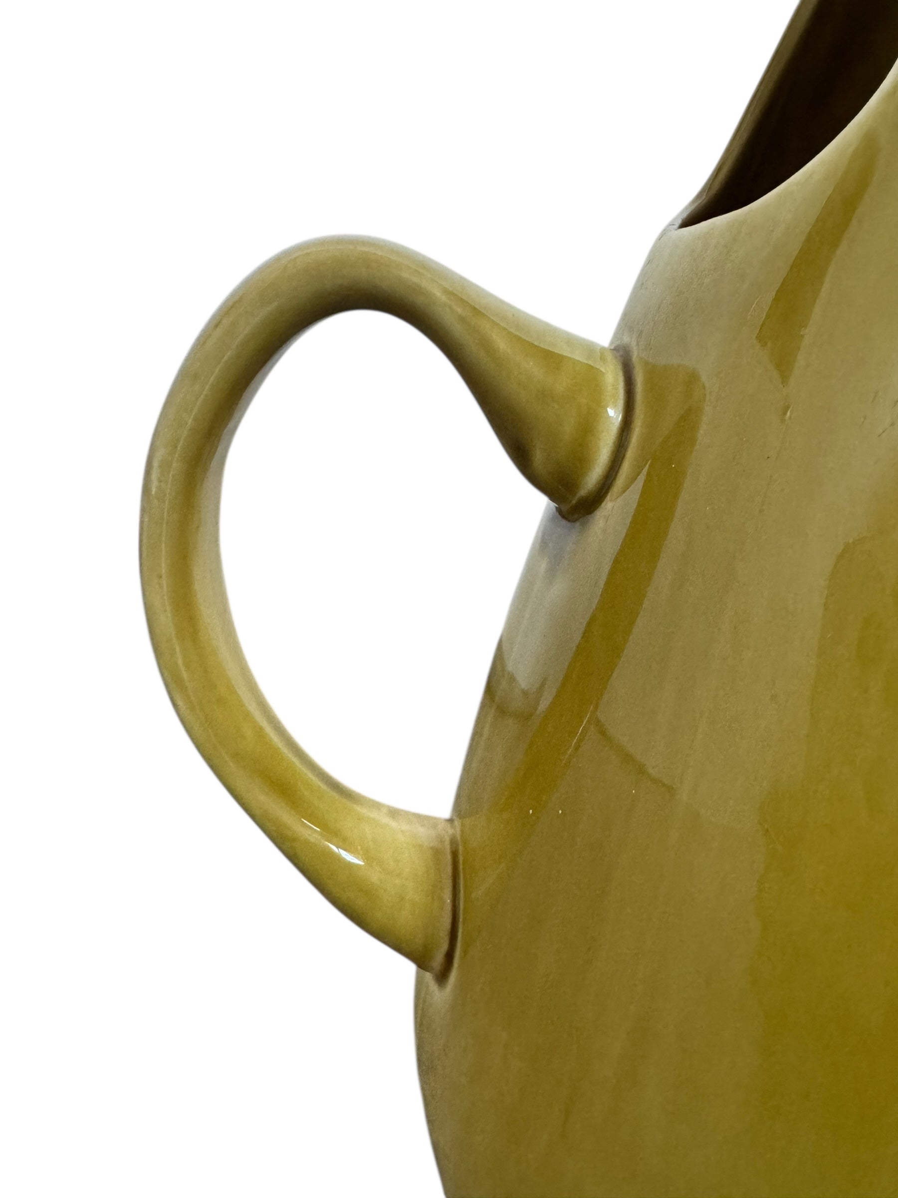 A chartreuse (yellow-green) ceramic pitcher designed by Russel Wright, featuring a teardrop shape, an elongated spout, and a curved handle