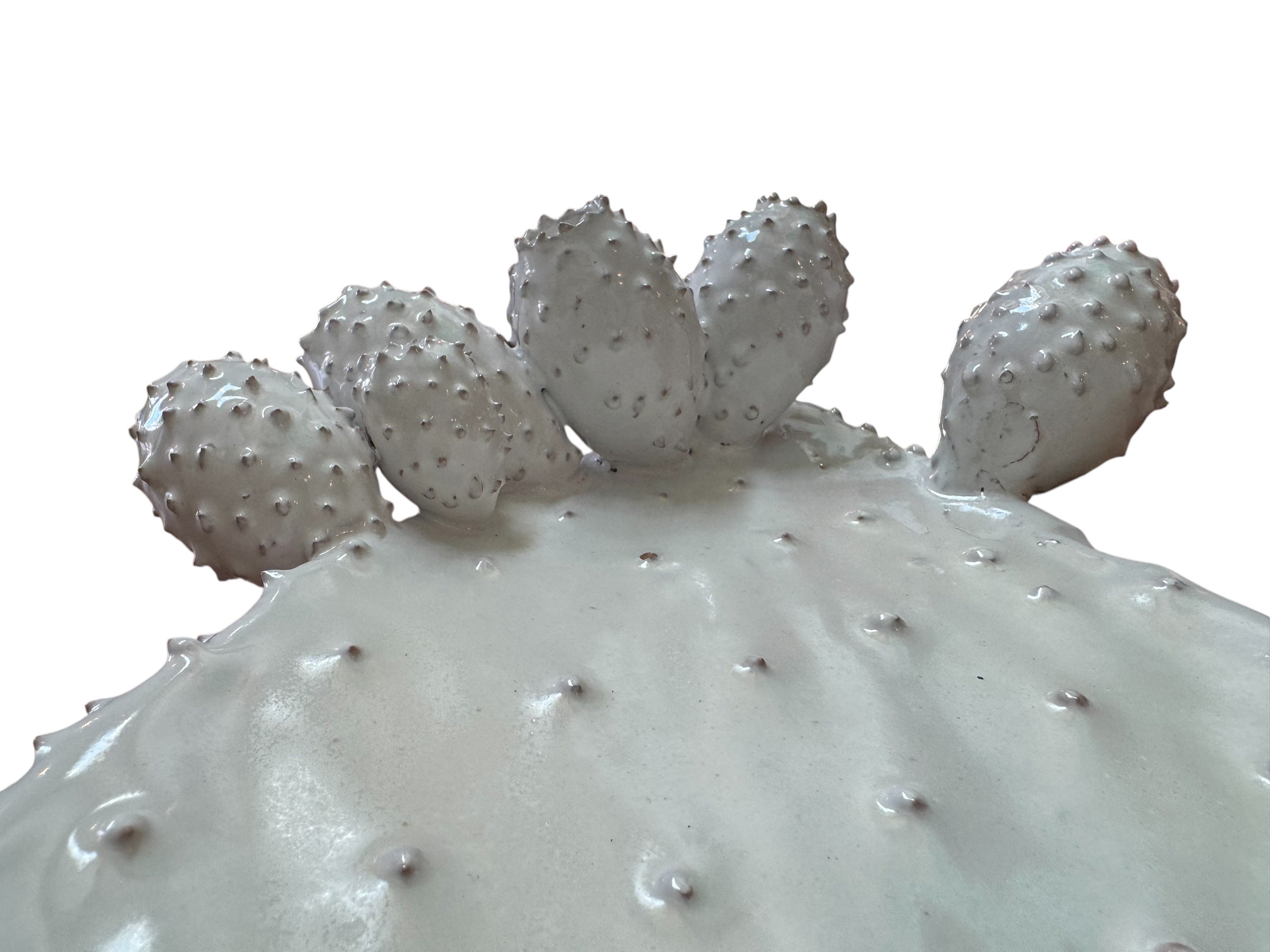 A white, glazed ceramic platter in the shape of a prickly pear cactus pad with attached prickly pear fruit. The surface has raised dots representing spines.