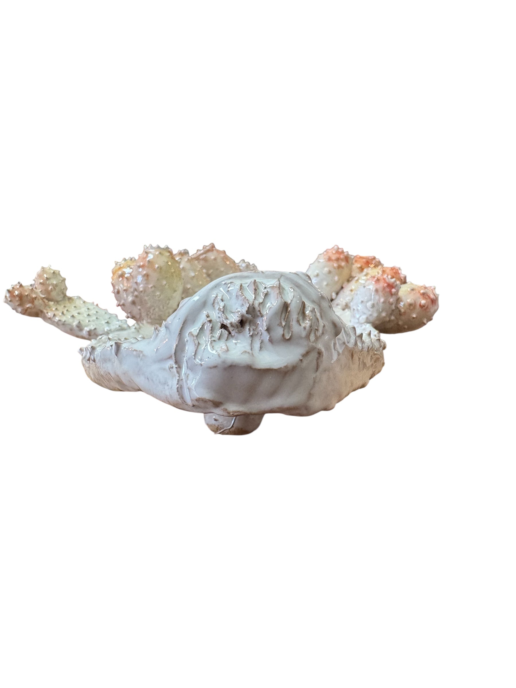 A white and orange, glazed ceramic platter in the shape of a prickly pear cactus pad with attached prickly pear fruit. The surface has raised dots representing spines.