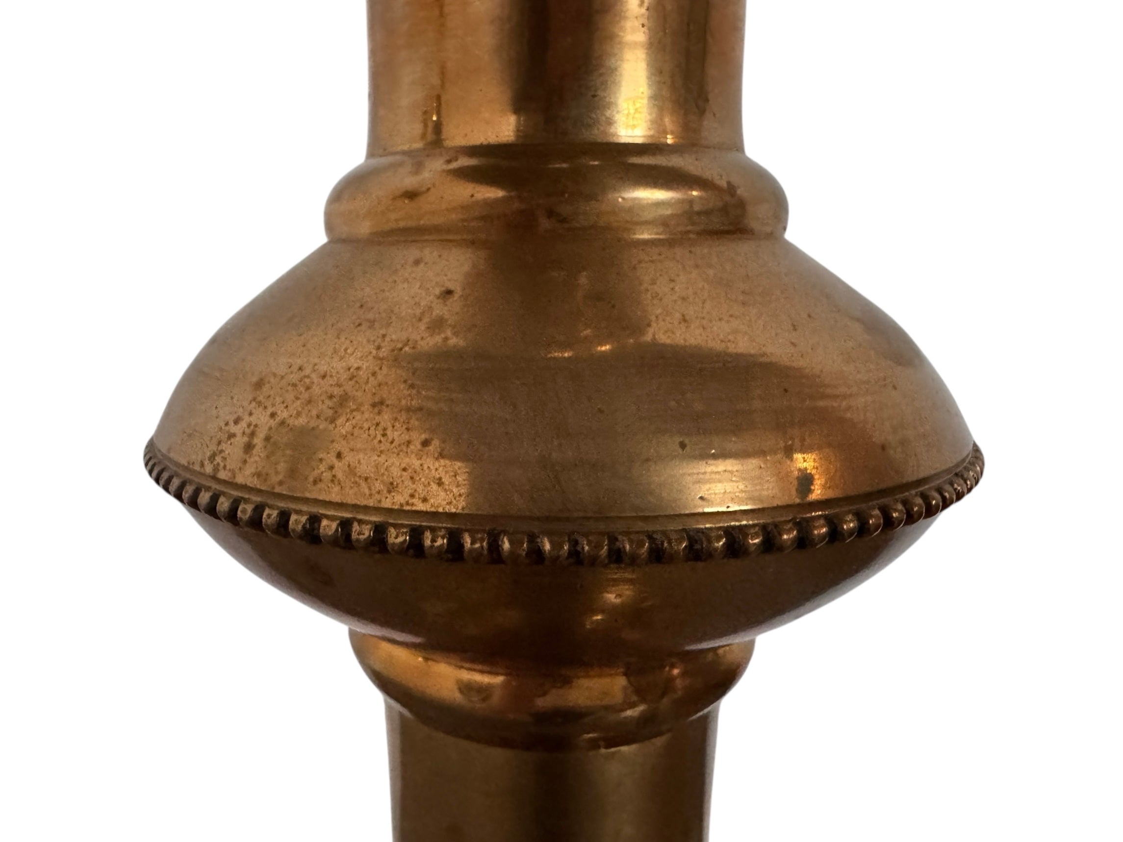 A tall, ornate, antique brass or bronze Gothic church candlestick holder with a pink candle in the top.