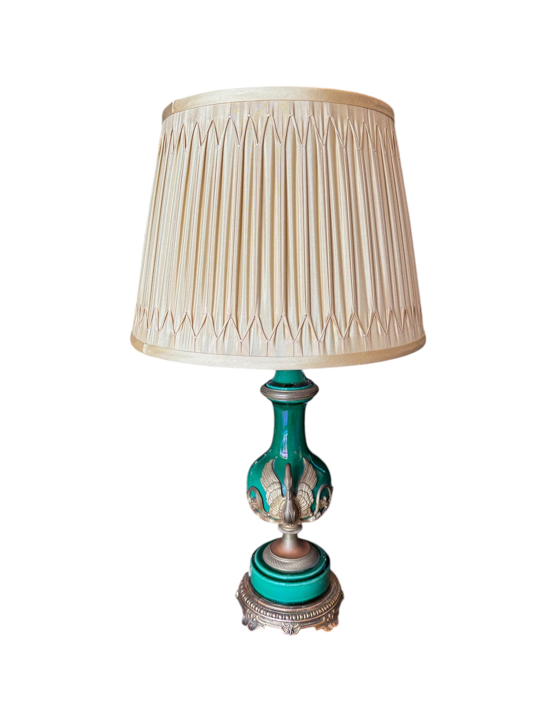 A vintage style lamp with a green vase-shaped base and gold ormolu details. It has an off white, pleated silk shade.