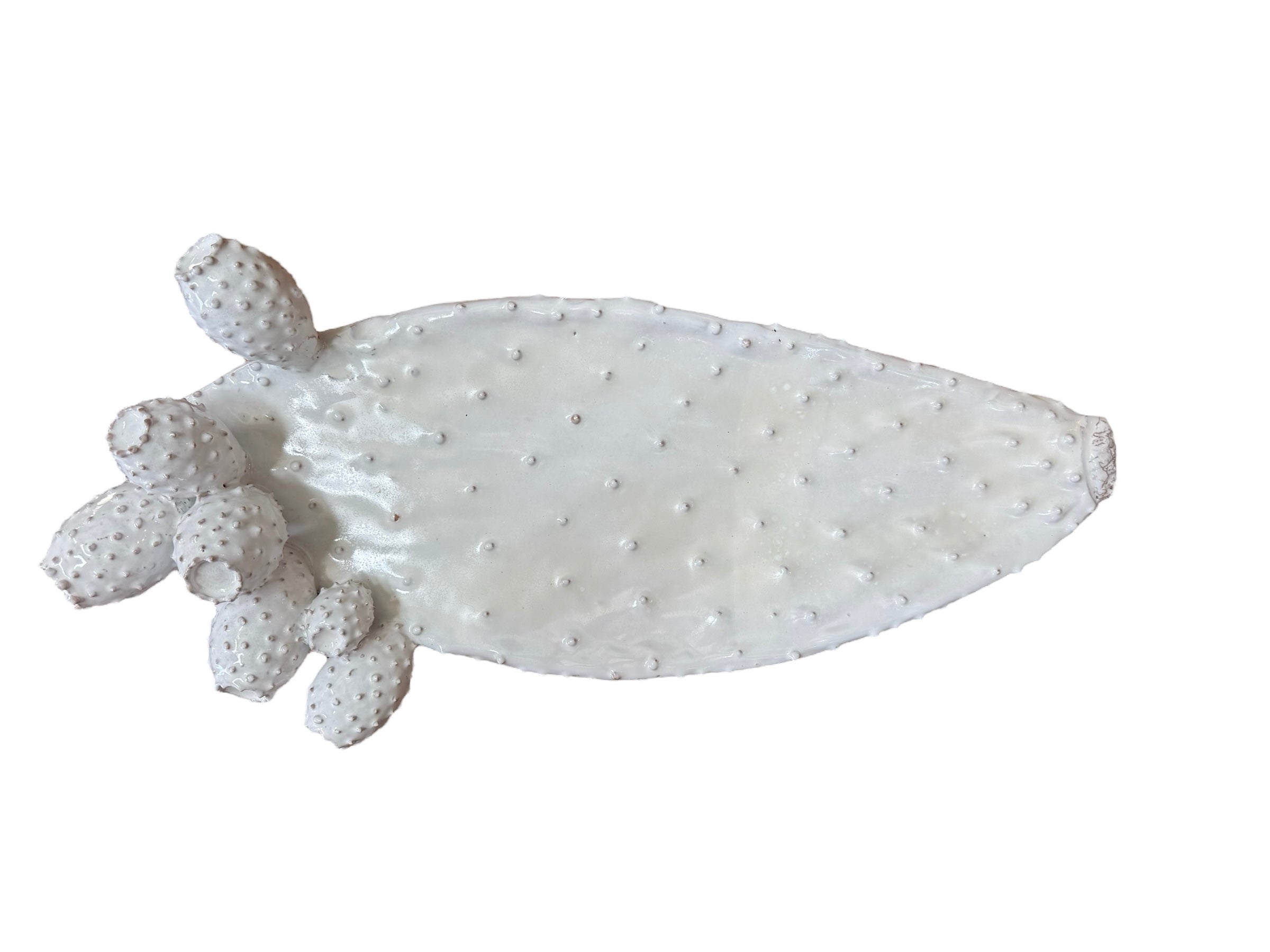 A white, glazed ceramic platter in the shape of a prickly pear cactus pad with attached prickly pear fruit. The surface has raised dots representing spines. 
Handmade White Cactus Platter - Italian Design by Enza Fasano Ceramiche