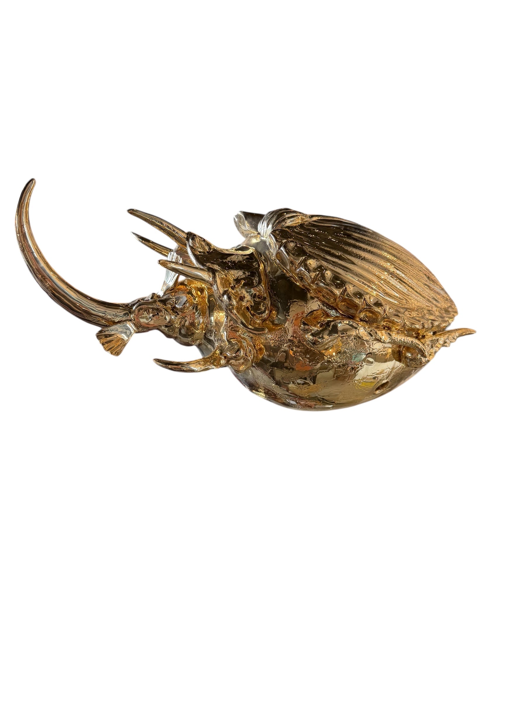 A handcrafted ceramic sculpture of a rhinoceros beetle by Enza Fasano, featuring a brilliant, high-gloss gold metallic finish. The beetle is captured in a dynamic, slightly upturned pose with detailed textures on its ribbed shell and prominent, curved horns. The piece reflects light across its polished surface, showcasing the artist’s signature fusion of traditional Pugliese pottery and contemporary luxury.