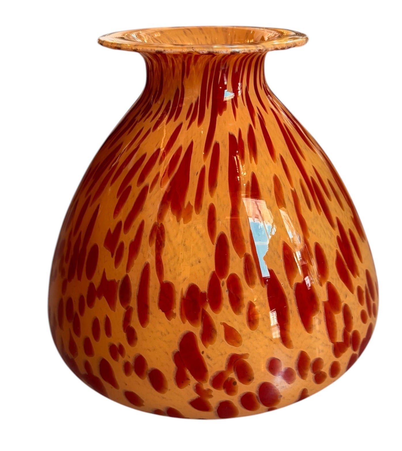 A hand-blown Italian Murano glass vase featuring a wide, bulbous body and a short, flared rim. The glass is a vibrant, translucent amber-orange base decorated with an organic "macchia" or spotted pattern of deep ruby red blotches. The red spots are elongated and vertical near the neck, becoming larger and more rounded toward the base. The surface has a high-gloss, reflective finish, showcasing mid-century modern craftsmanship.