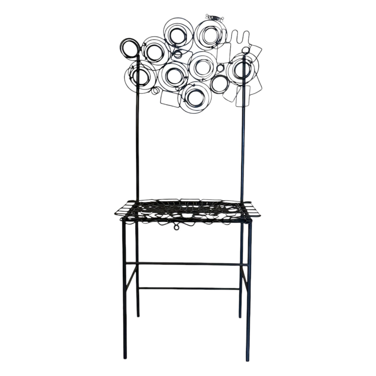 A metal chair by Susan Woods with a unique design featuring circular elements at the top, a flat seat, and a traditional backrest, all in black. Musical chair.
