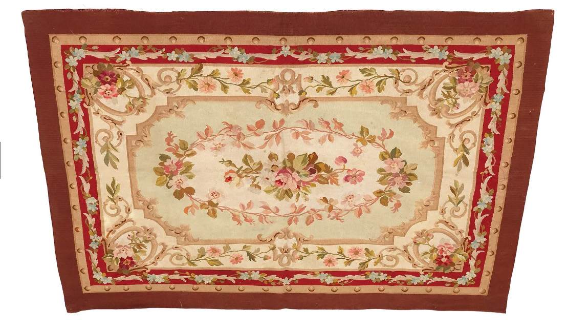 An antique-style Aubusson tapestry rug featuring a central floral medallion on a pale mint green field. The medallion is composed of pink roses and lush greenery, enclosed within a scalloped, sandy-beige border.