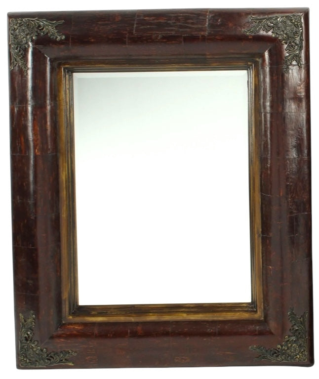 Antique-style mirror with a dark wooden frame and brass accents, viewed from a slight angle against a plain background.