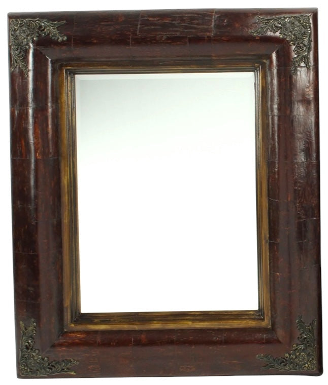 Antique-style mirror with a dark wooden frame and brass accents, viewed from a slight angle against a plain background.