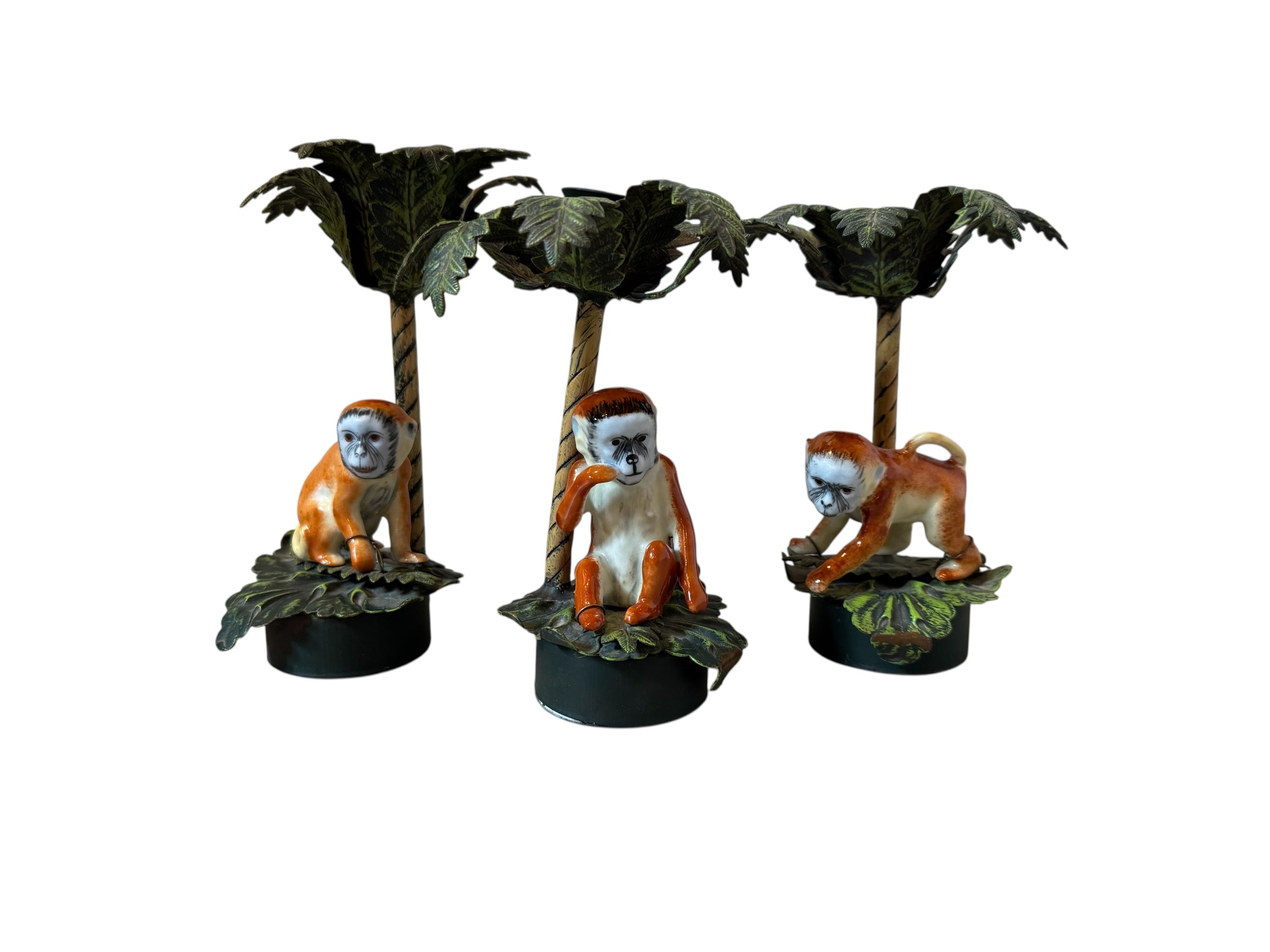 Three monkey figurines with orange and white fur on black bases with palm tree decorations.
Petite Choses Vintage Palm Tree Monkey Candlestick Set
