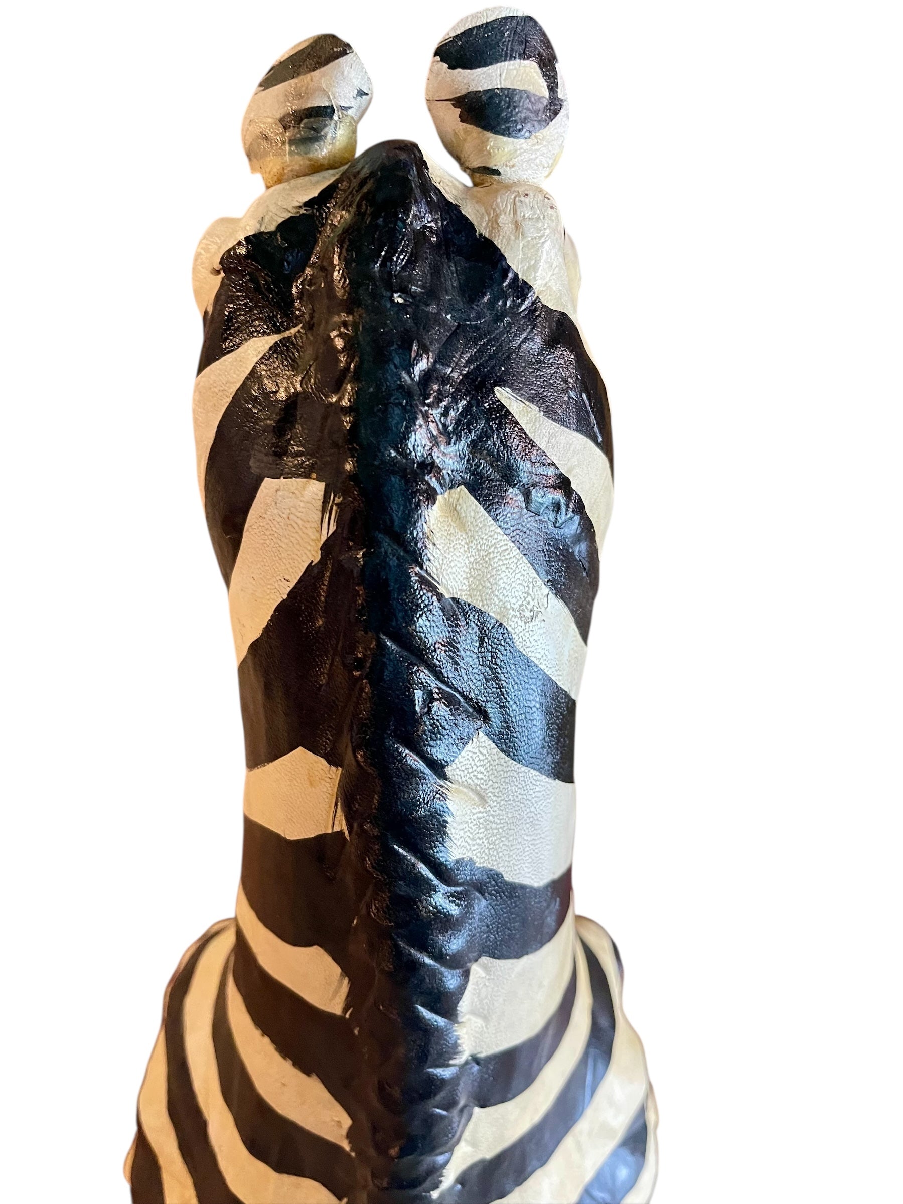 A full-length view of a standing zebra sculpture made from hand-painted leather. The sculpture features bold black and white stripes and shows signs of age, including slight yellowing and a tear on its leg.
Vintage
Antique
Art
Figurine
Decorative
Animal
Wear
Tear
Cream
Standing
Detailed
Full-length
Close-up