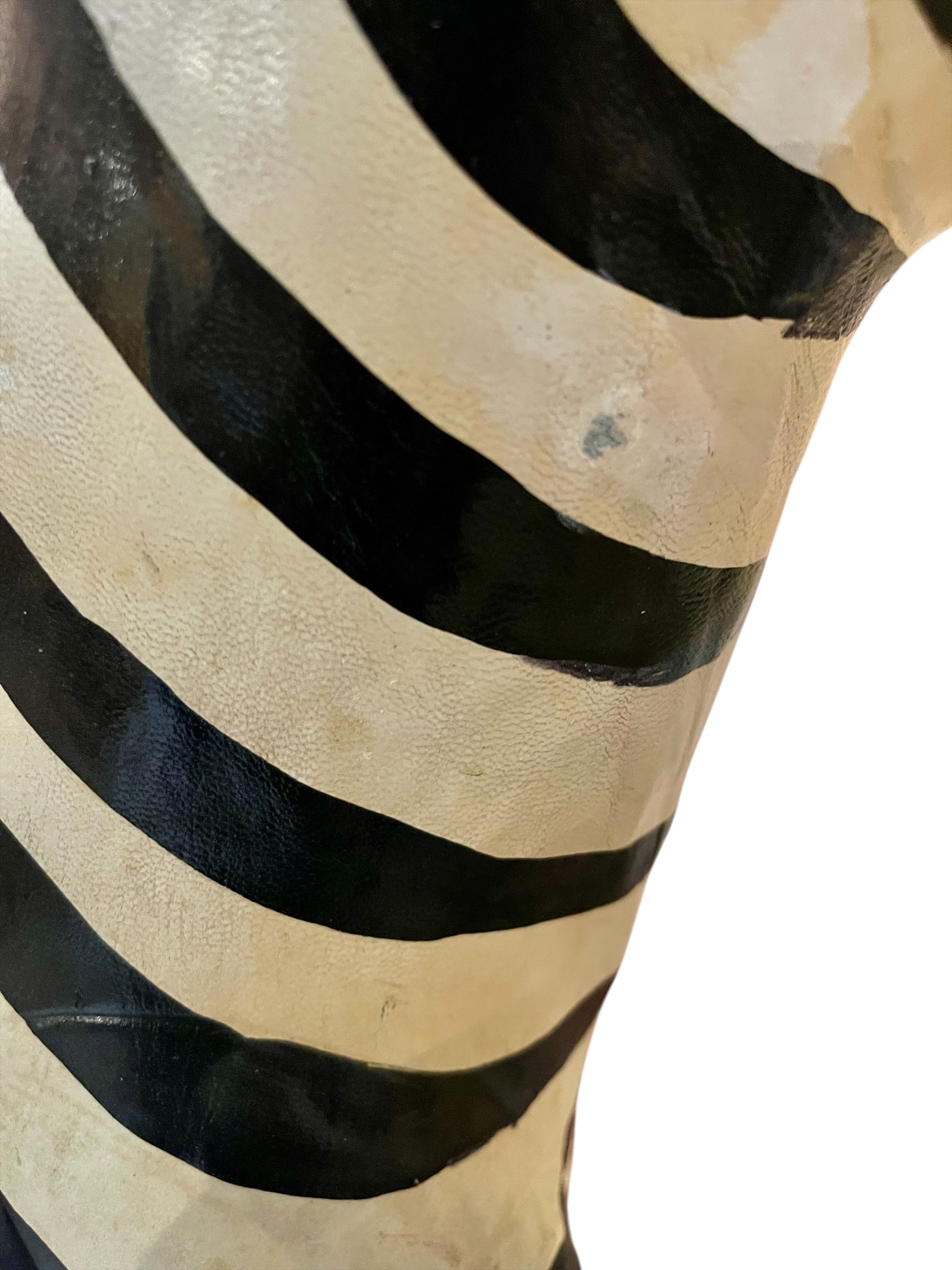 A full-length view of a standing zebra sculpture made from hand-painted leather. The sculpture features bold black and white stripes and shows signs of age, including slight yellowing and a tear on its leg.
Vintage
Antique
Art
Figurine
Decorative
Animal
Wear
Tear
Cream
Standing
Detailed
Full-length
Close-up
