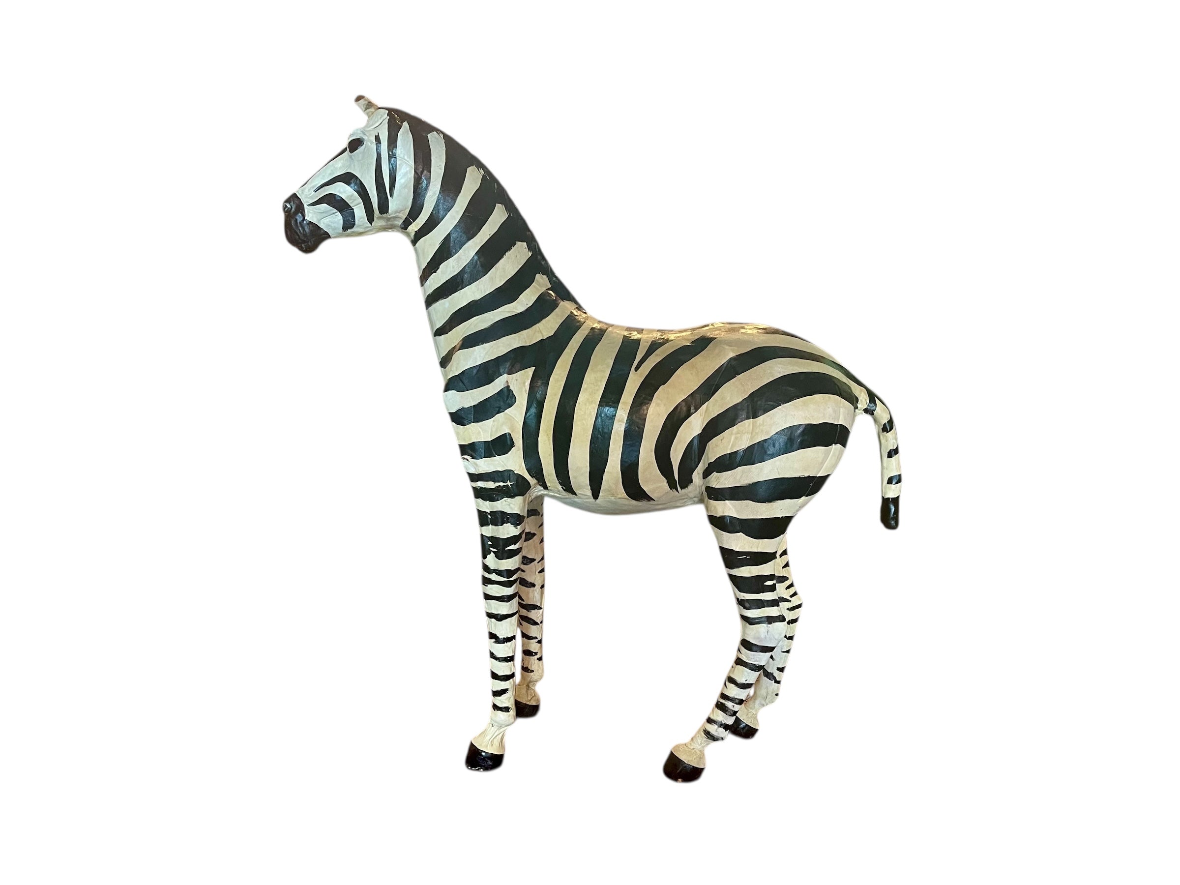A full-length view of a standing zebra sculpture made from hand-painted leather. The sculpture features bold black and white stripes and shows signs of age, including slight yellowing and a tear on its leg.
Vintage
Antique
Art
Figurine
Decorative
Animal
Wear
Tear
Cream
Standing
Detailed
Full-length
Close-up