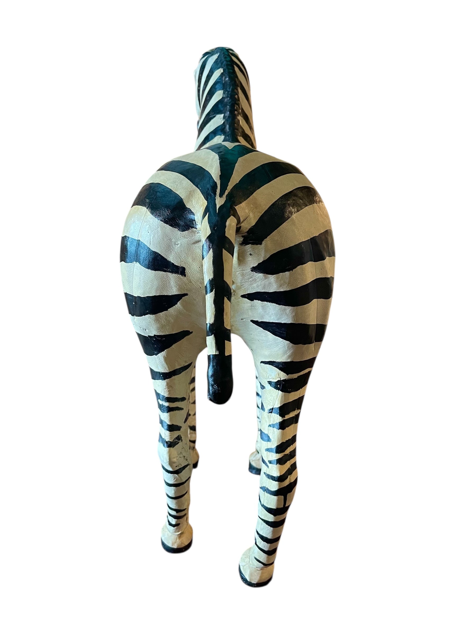 A full-length view of a standing zebra sculpture made from hand-painted leather. The sculpture features bold black and white stripes and shows signs of age, including slight yellowing and a tear on its leg.
Vintage
Antique
Art
Figurine
Decorative
Animal
Wear
Tear
Cream
Standing
Detailed
Full-length
Close-up