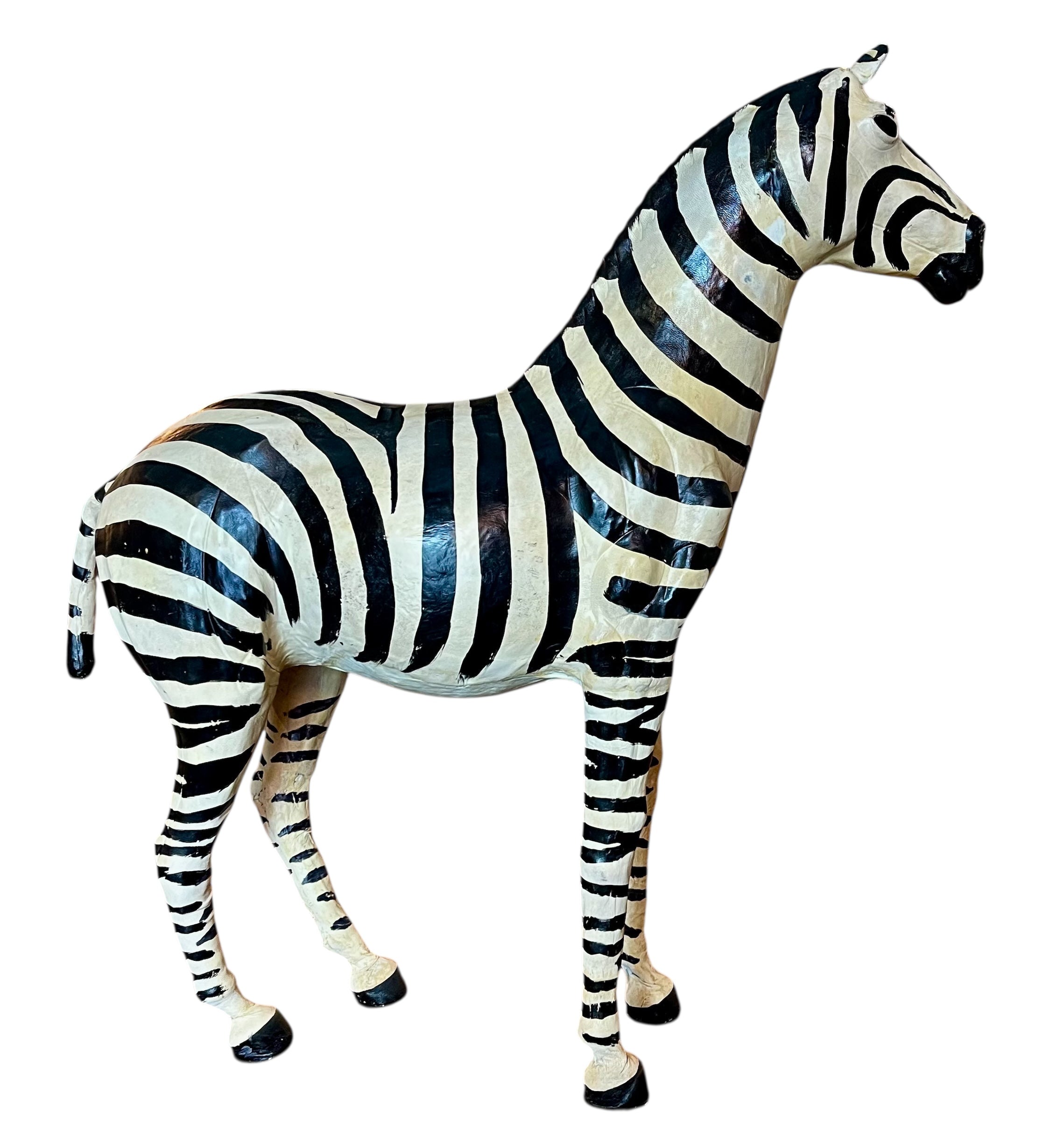 A full-length view of a standing zebra sculpture made from hand-painted leather. The sculpture features bold black and white stripes and shows signs of age, including slight yellowing and a tear on its leg.
Vintage
Antique
Art
Figurine
Decorative
Animal
Wear
Tear
Cream
Standing
Detailed
Full-length
Close-up