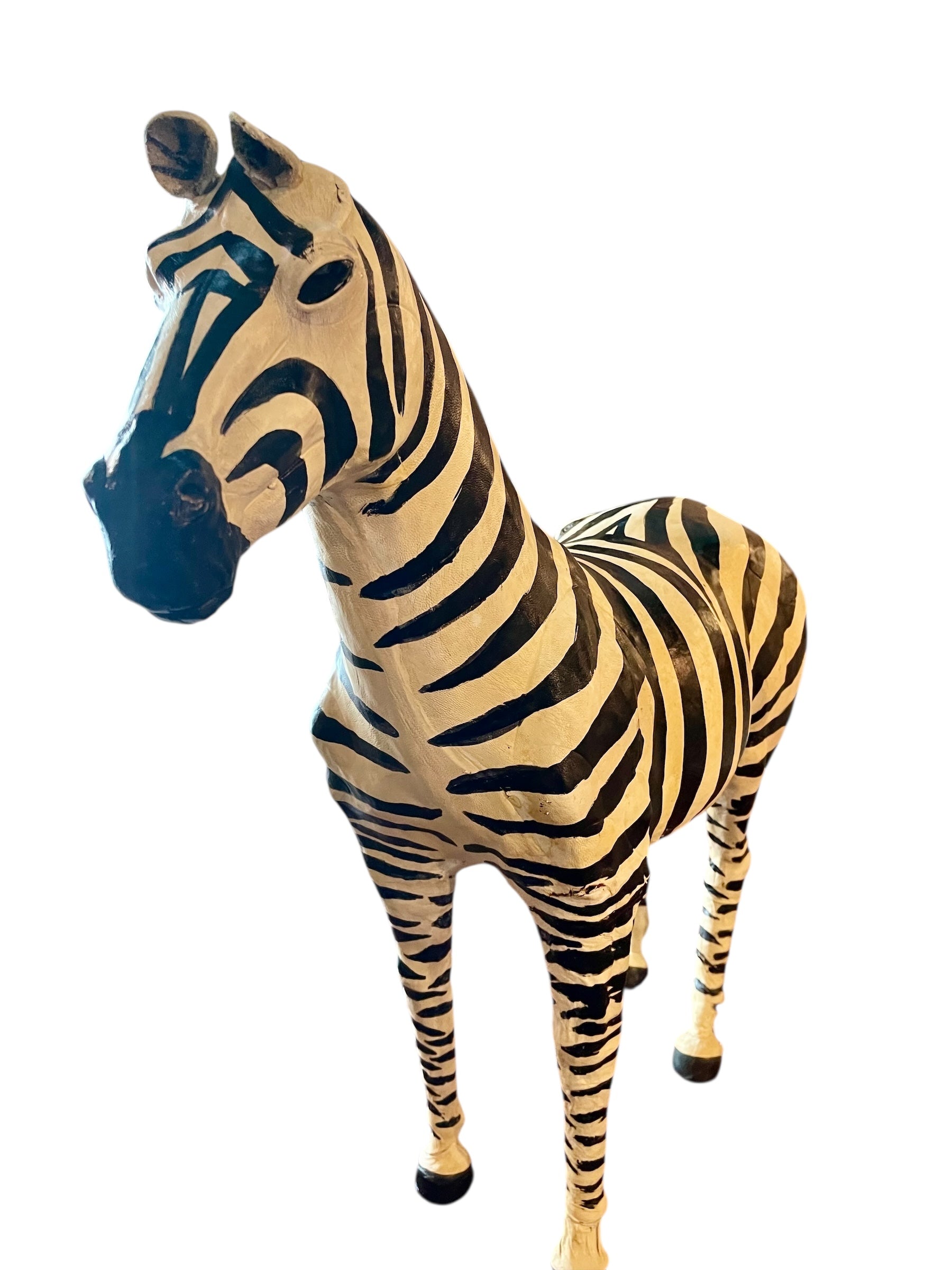 A full-length view of a standing zebra sculpture made from hand-painted leather. The sculpture features bold black and white stripes and shows signs of age, including slight yellowing and a tear on its leg.
Vintage
Antique
Art
Figurine
Decorative
Animal
Wear
Tear
Cream
Standing
Detailed
Full-length
Close-up