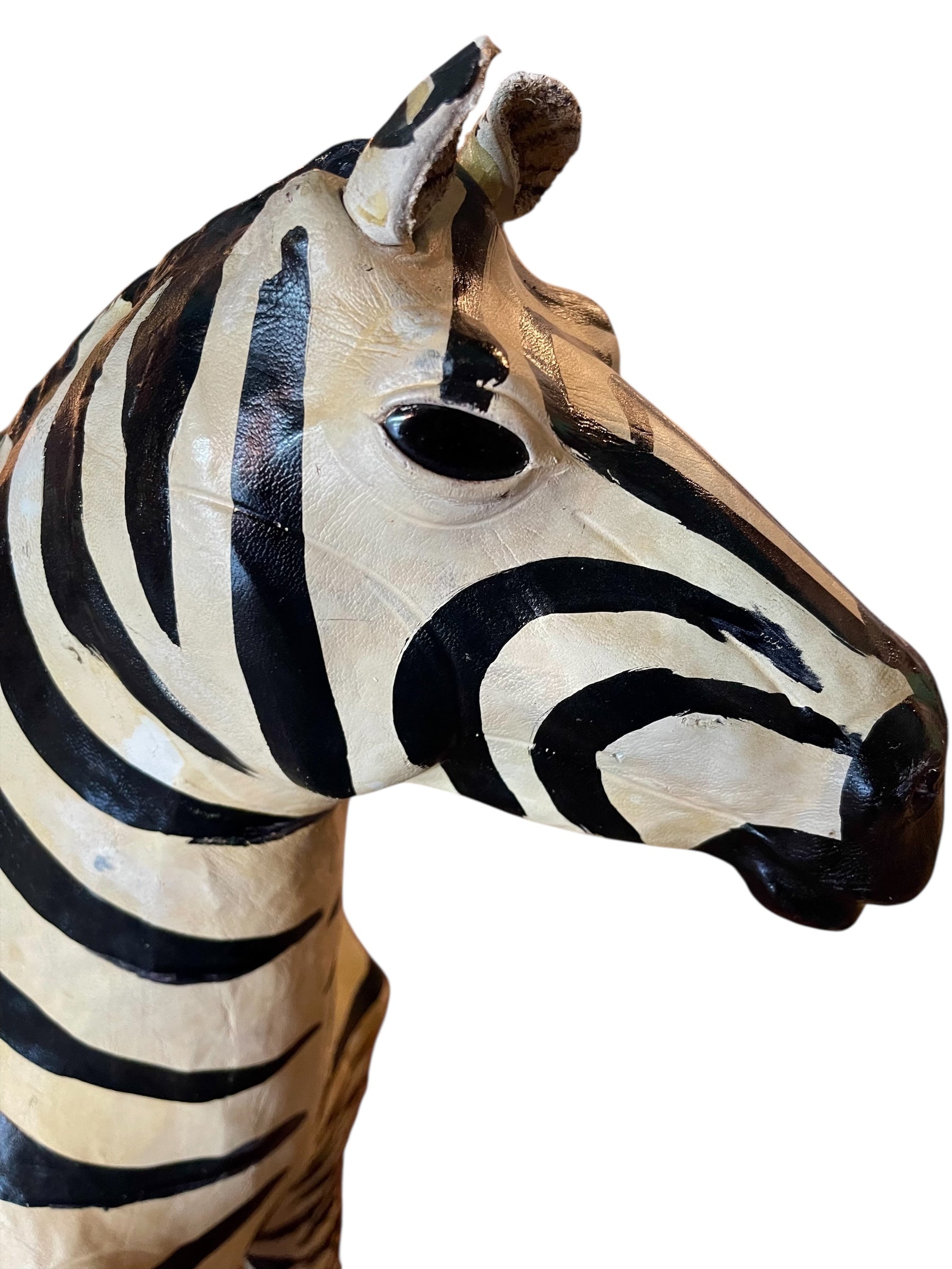 A full-length view of a standing zebra sculpture made from hand-painted leather. The sculpture features bold black and white stripes and shows signs of age, including slight yellowing and a tear on its leg.
Vintage
Antique
Art
Figurine
Decorative
Animal
Wear
Tear
Cream
Standing
Detailed
Full-length
Close-up
