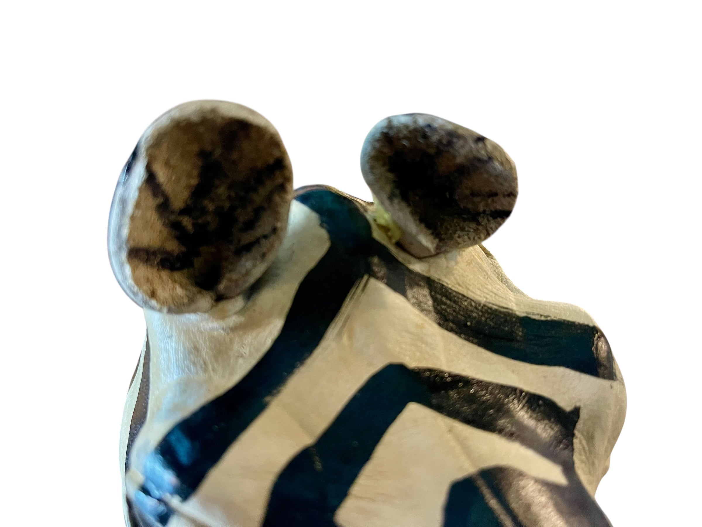 A full-length view of a standing zebra sculpture made from hand-painted leather. The sculpture features bold black and white stripes and shows signs of age, including slight yellowing and a tear on its leg.
Vintage
Antique
Art
Figurine
Decorative
Animal
Wear
Tear
Cream
Standing
Detailed
Full-length
Close-up