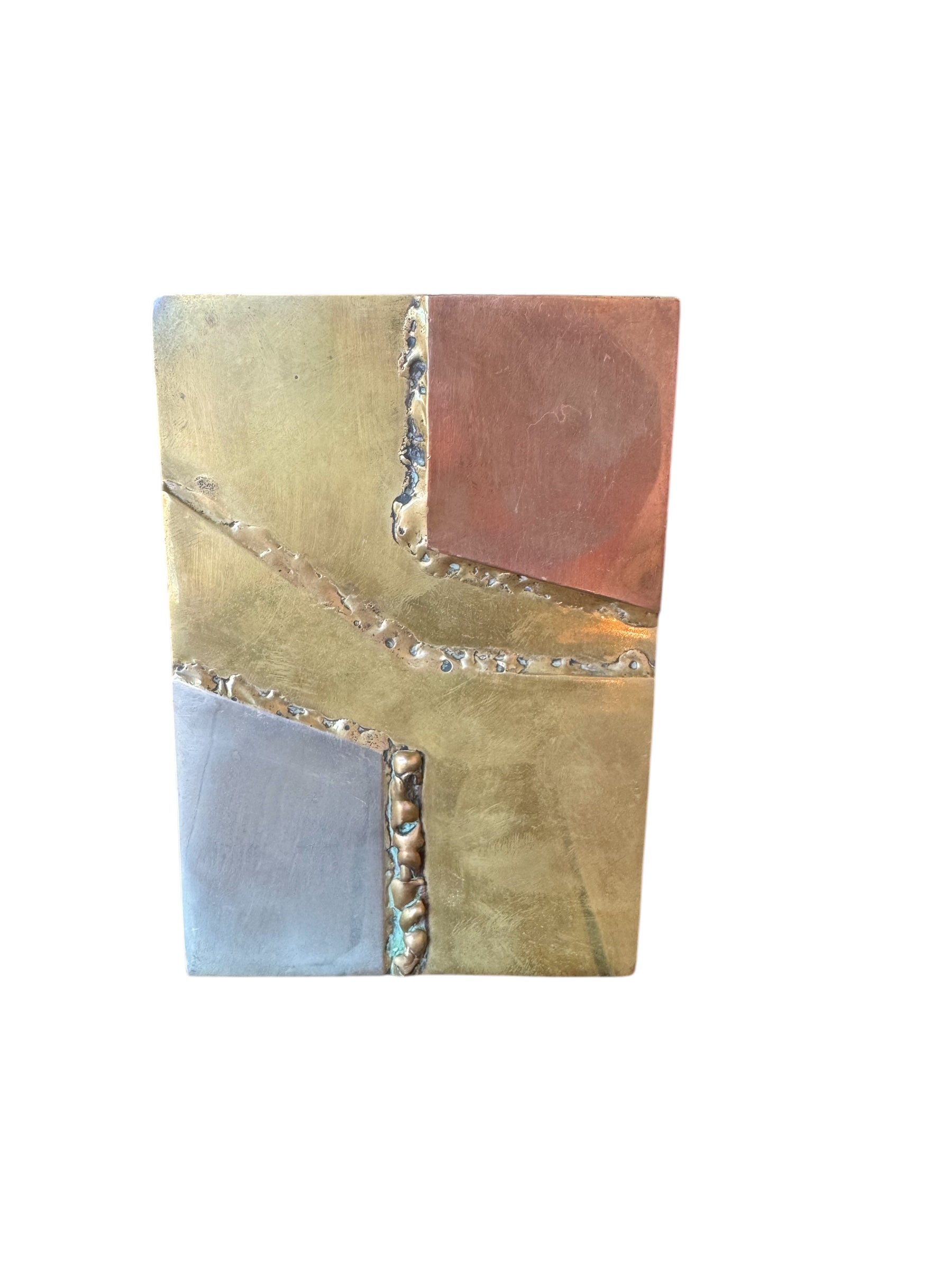 Close-up of two David Marshall Brutalist bookends. The bookends feature contrasting silver and bronze metal panels, separated by raised textured bronze seams. The bookends have a rough, geometric design.