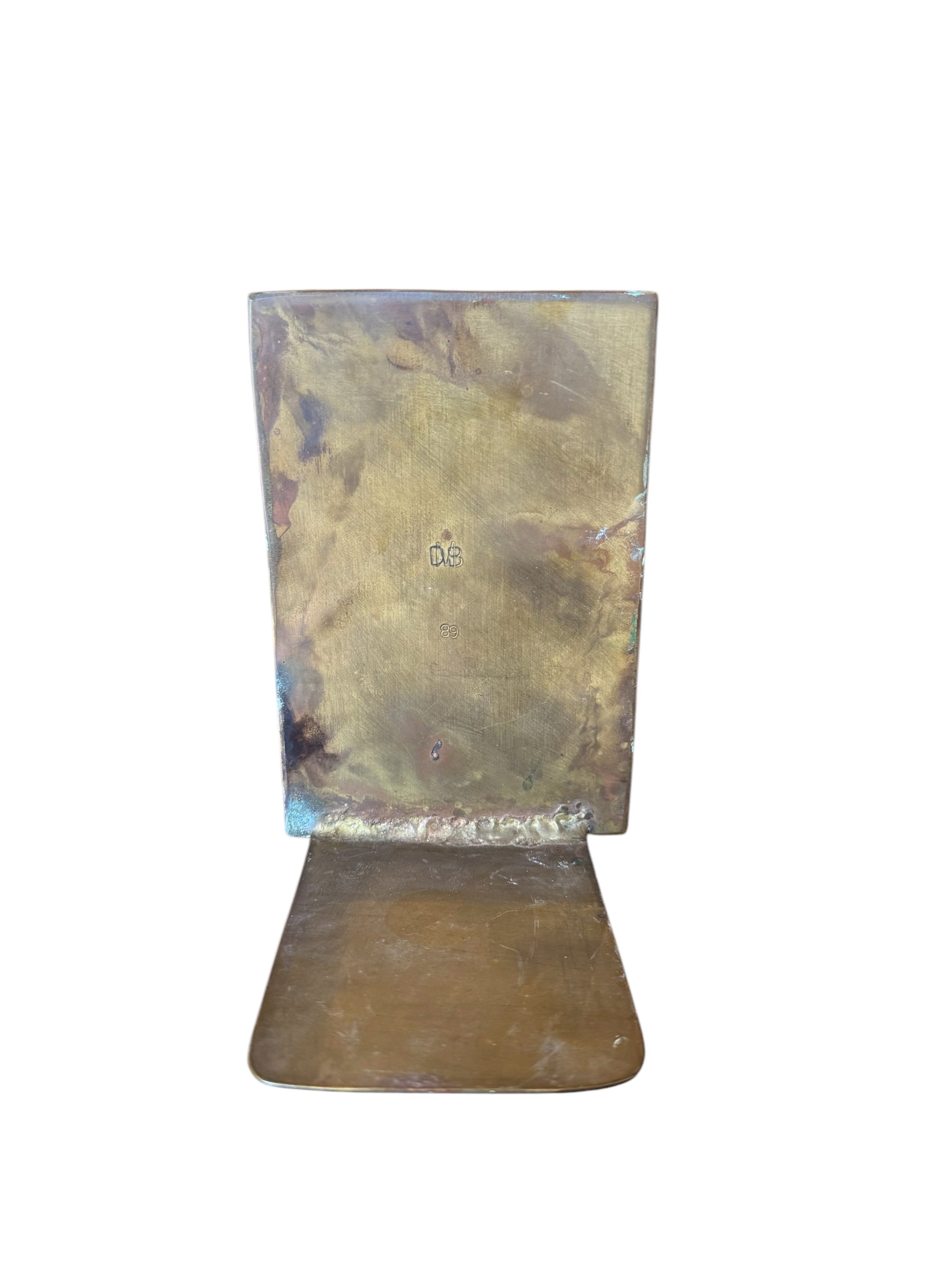 Close-up of two David Marshall Brutalist bookends. The bookends feature contrasting silver and bronze metal panels, separated by raised textured bronze seams. The bookends have a rough, geometric design.