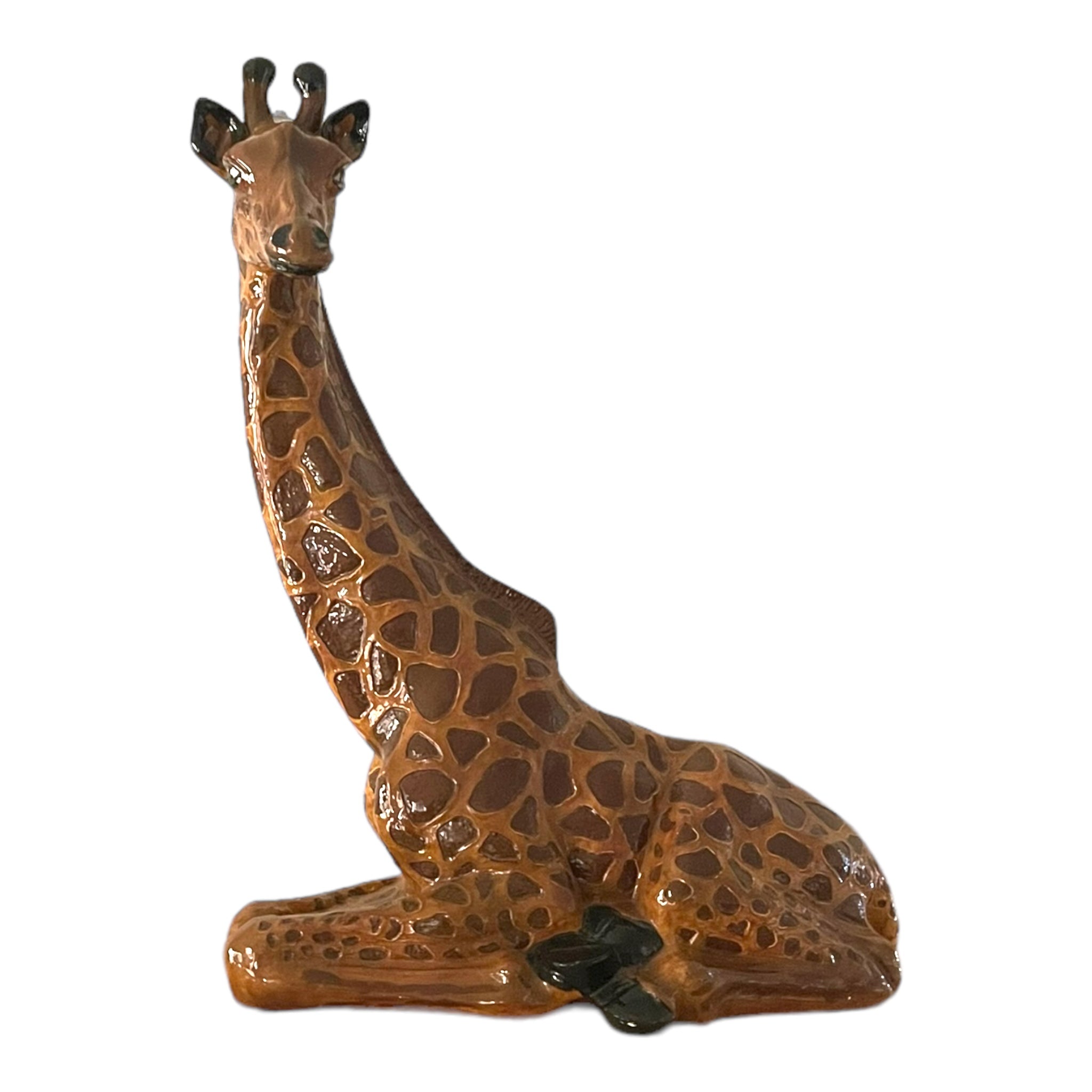 A ceramic figurine of a giraffe with hand-painted details, showing the animal in a standing position with its neck extended.