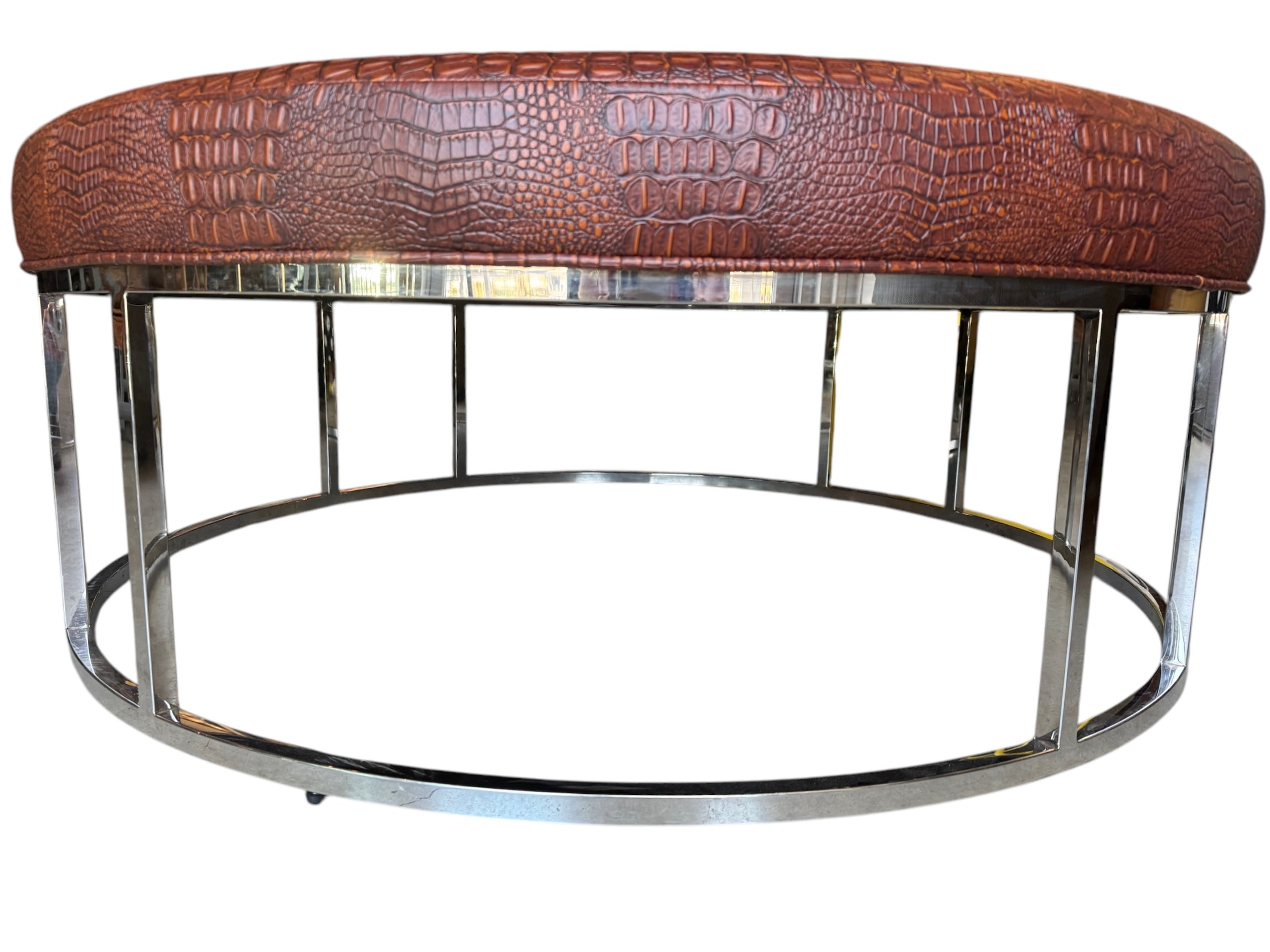 A large round ottoman with a croc-embossed brown vinyl cushion and a silver chrome base by Mitchell Gold and Bob Williams.