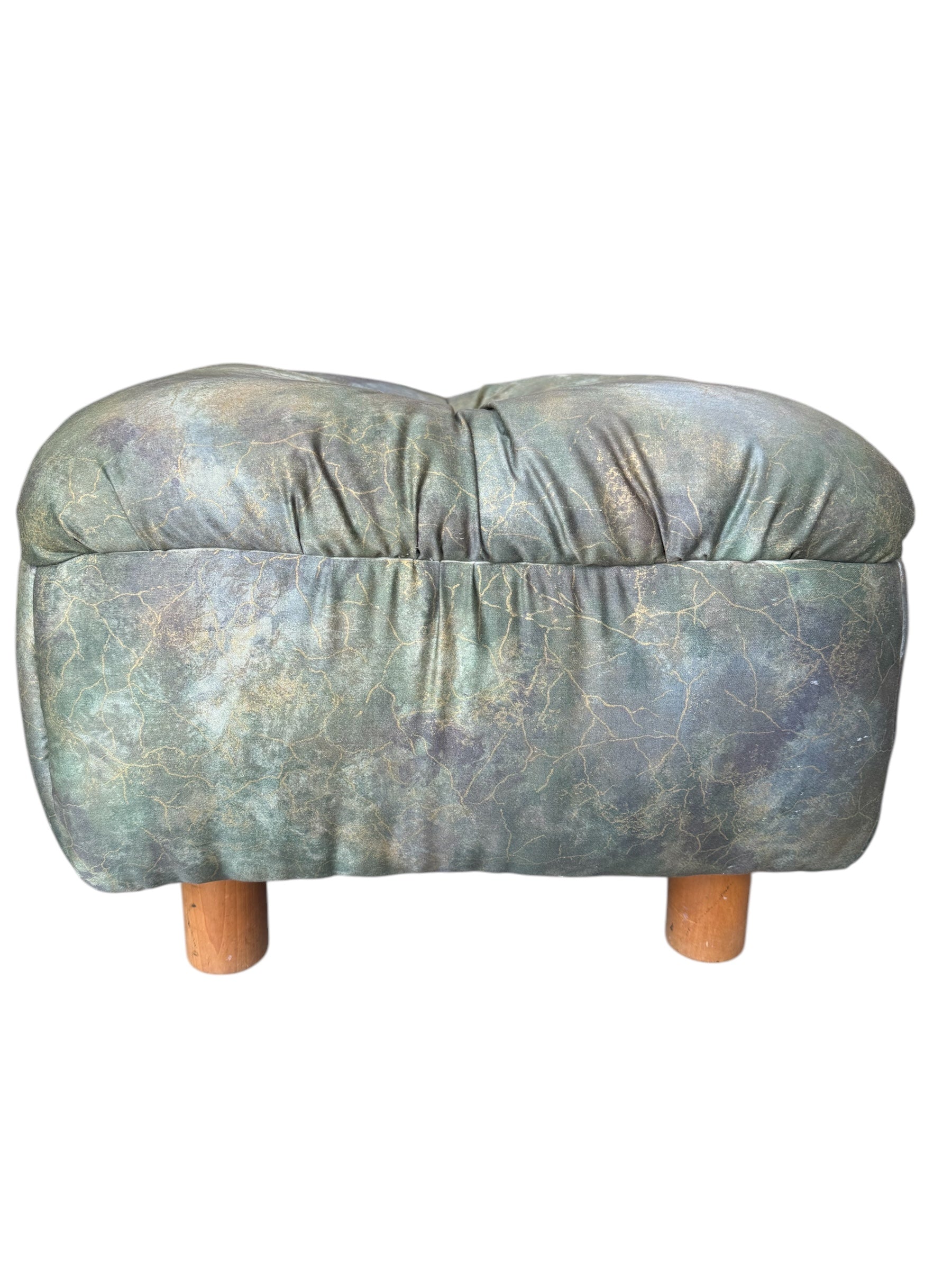 A vintage 1990s ottoman with a mottled green, blue, and gold upholstery, tufted top, and wooden feet.