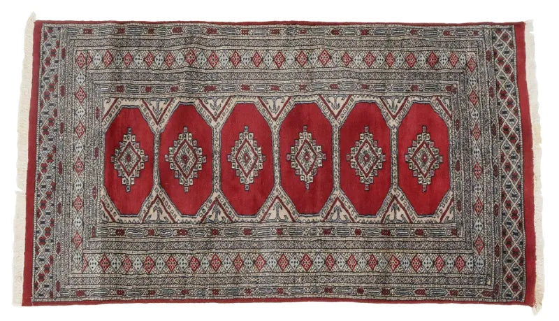 A vintage deep red and beige Pakistan Karachi rug with geometric patterns.
