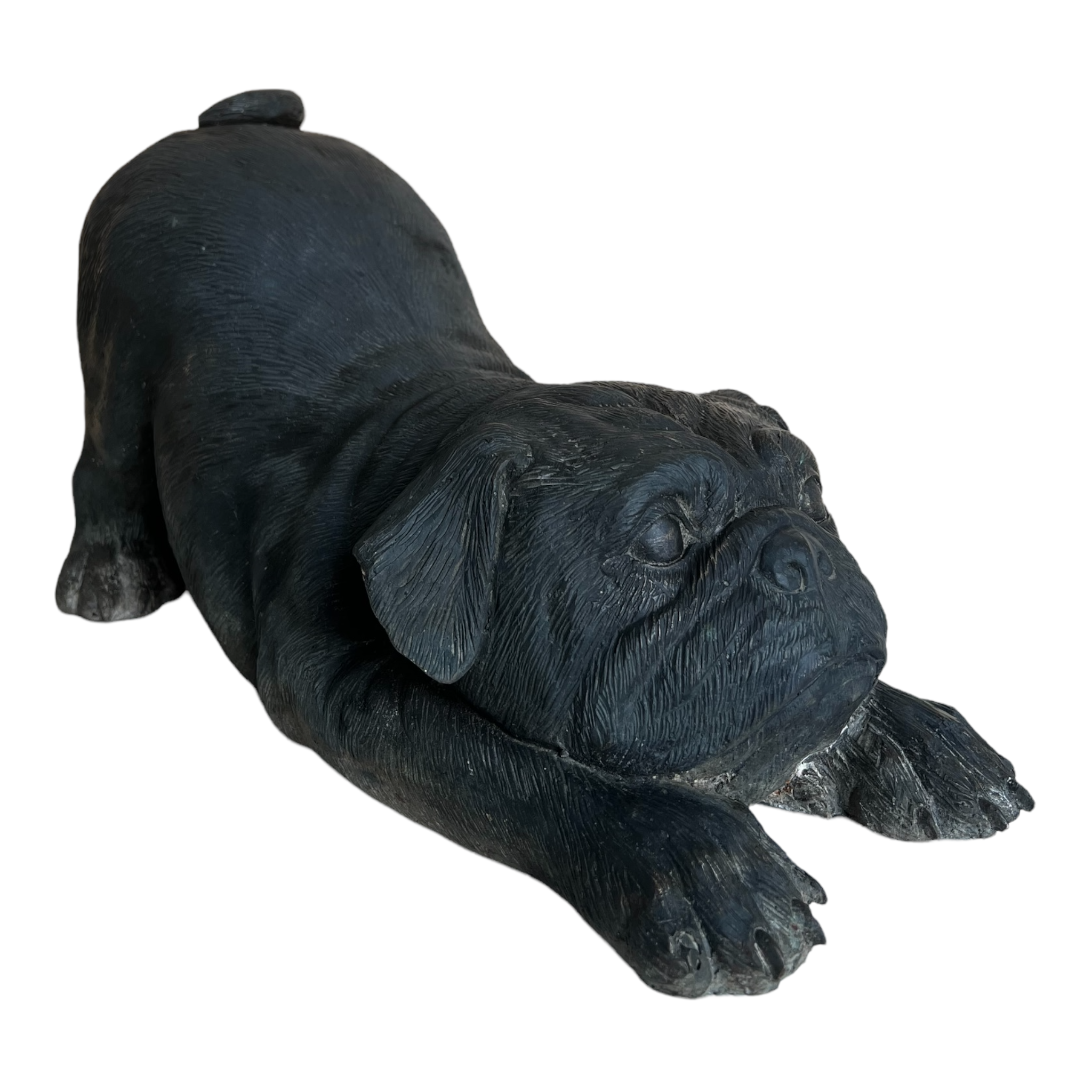 Life size brass sculpture of a pug dog with a patina finish, in a playful lying pose.