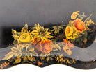 A vintage rectangular toleware serving tray with a scalloped, wavy edge and a black lacquered finish. The tray features hand-painted floral motifs in a traditional folk-art style. At the bottom center is a large, vibrant cluster of yellow and orange roses and daisies with green leaves. Smaller floral sprays and delicate gold filigree scrollwork decorate the corners and the upper rim. The center of the tray is open black space, showing light surface wear and minor scuffing consistent with age.