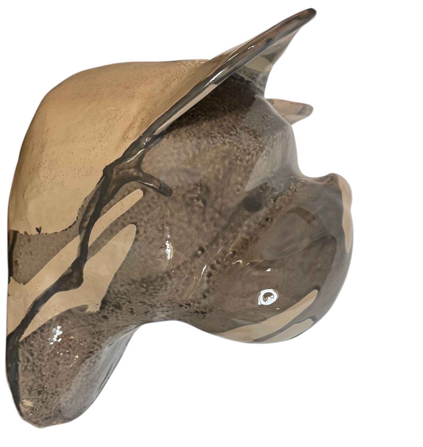 A ceramic sculpture of a bulldog's head by Enza Fasano. The piece features a glossy, glazed finish with a sophisticated color palette of muted greys, creams, and earthy brown tones arranged in bold, abstract striped patterns across the face and ears. The bulldog has characteristic folded ears, a prominent snout, and a soulful, slightly downturned expression. The sculpture is set against a clean, white background, highlighting its smooth texture and reflective surface.