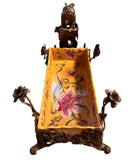 A rectangular yellow porcelain jardiniere with hand-painted red flowers and green foliage, mounted in ornate gilt bronze. The bronze features scrolled feet, delicate floral stems, and a winged fairy nymph figure perched on one side.

