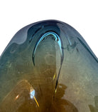 A vintage, hand-blown art glass bowl with a wavy, organic shape and a blue and amber/yellow swirl design