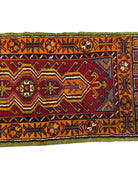 Anatolian Yastik rug with red, gold, green and gray geometric patterns and fringe.
